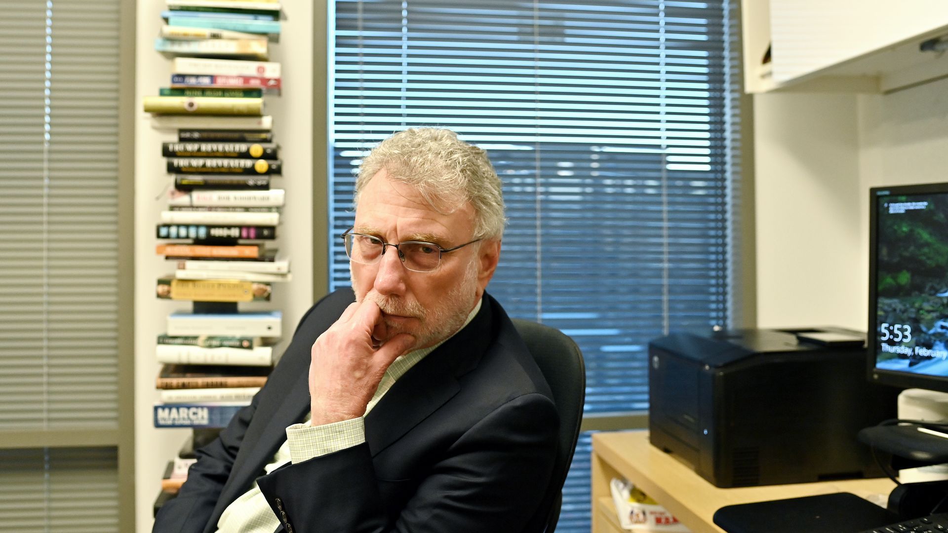 Marty Baron sits at his desk in front of a pile of books