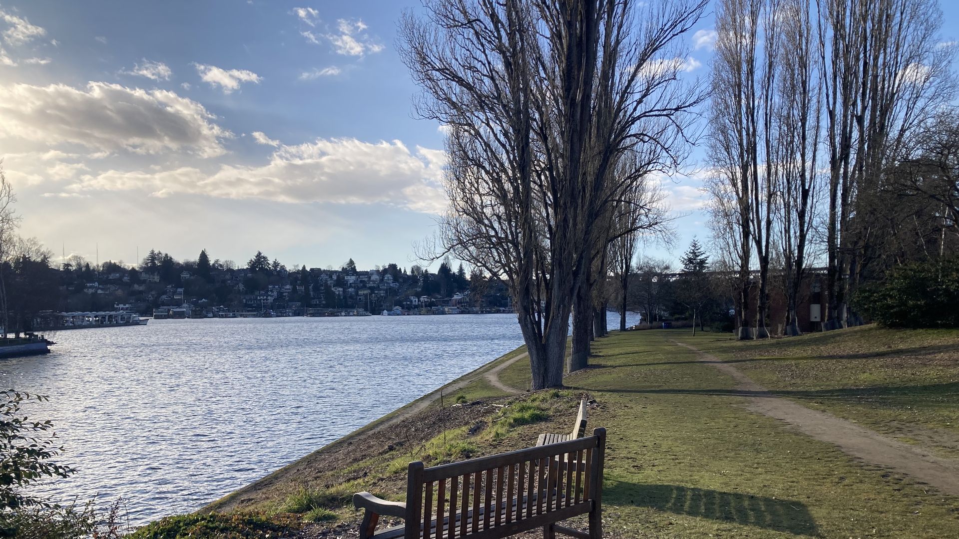 An empty bench along a cut of water with walking trails nearby. 