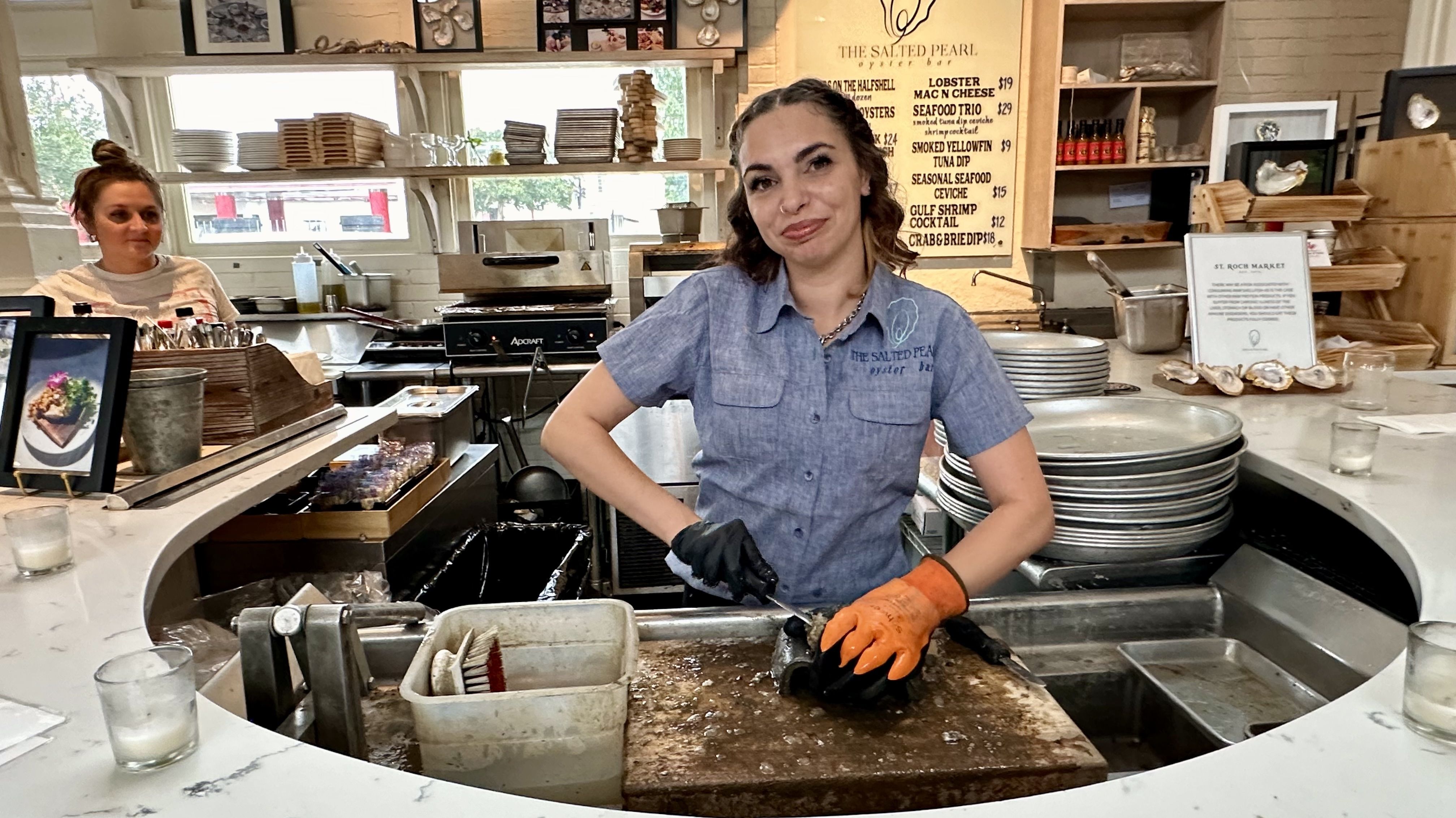 Image shows a woman opening an oyster.