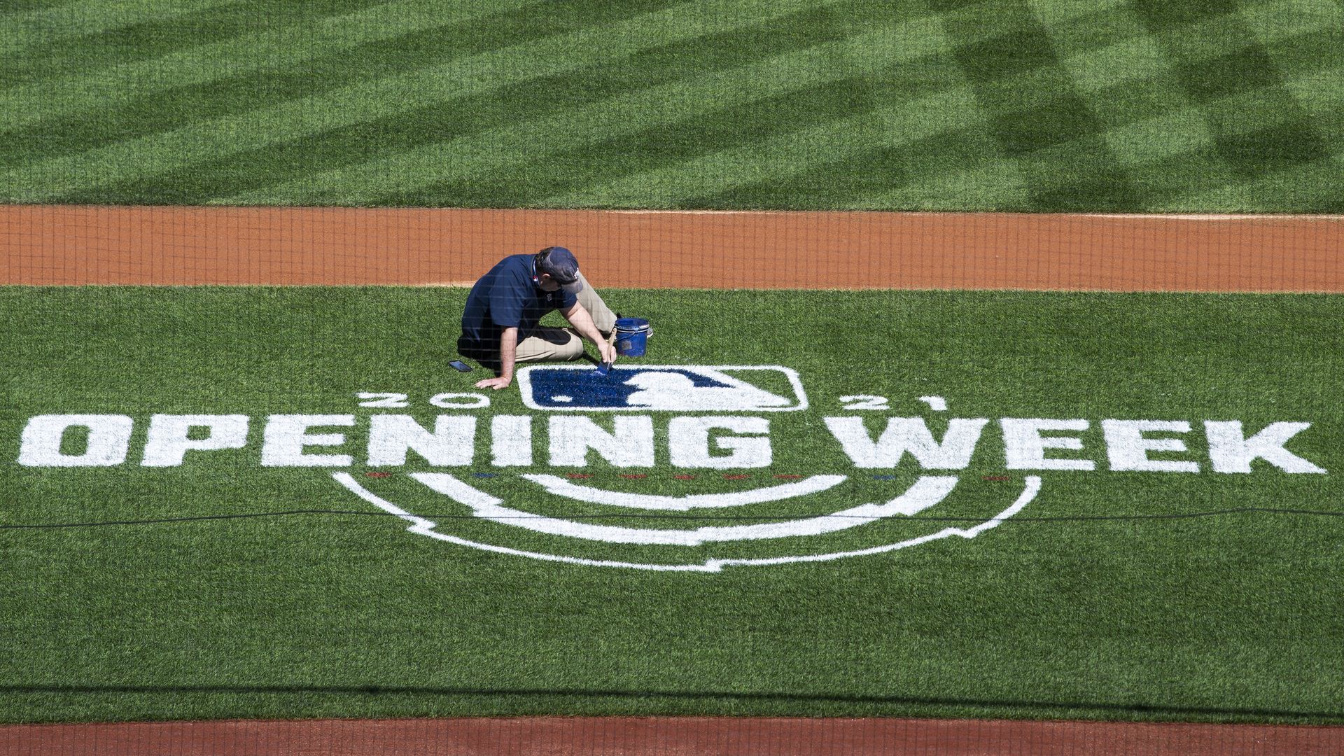 Photo of a person painting the field with words Opening Week