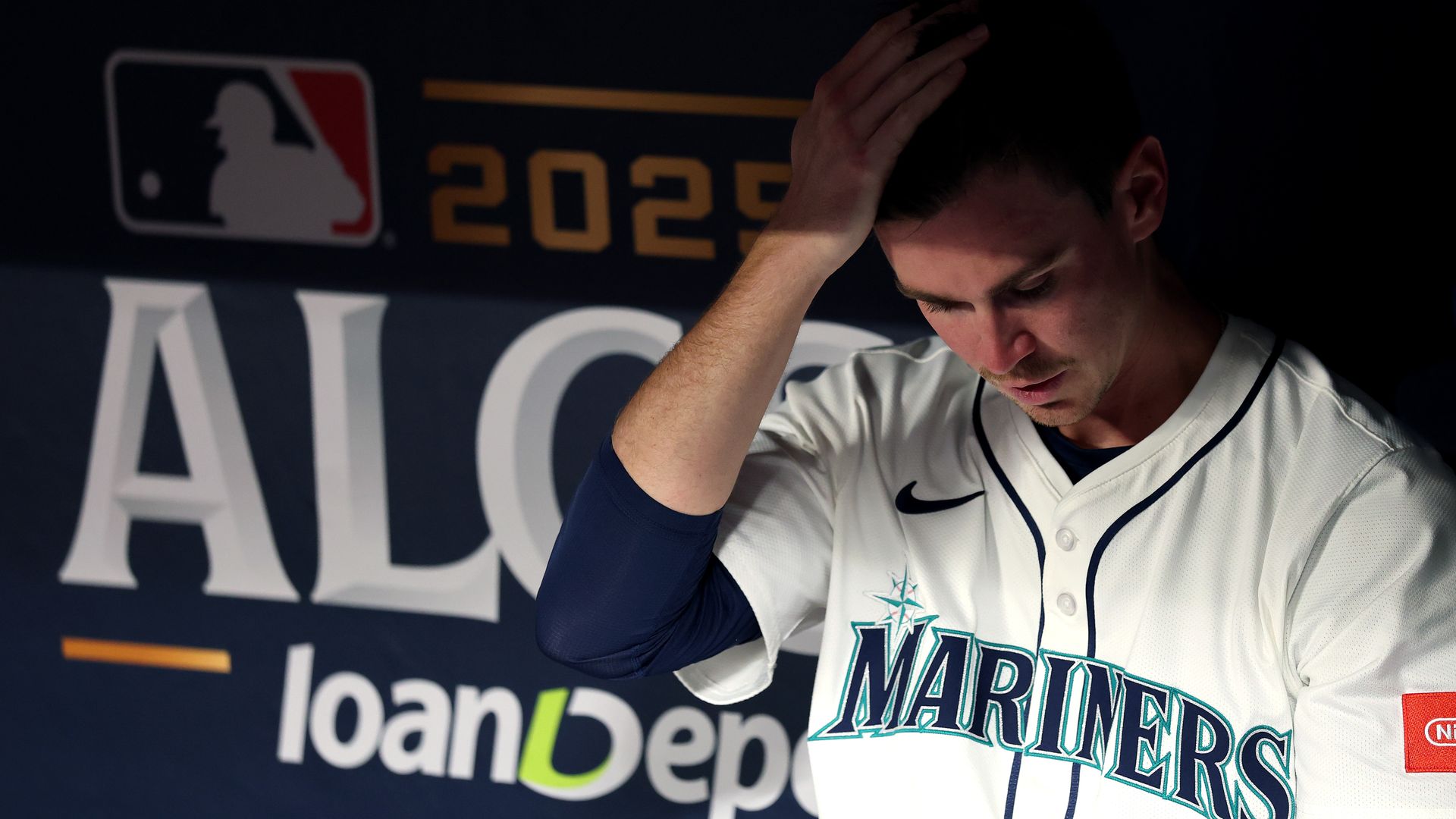 A Mariners ball player hangs his head while his team loses to the Blue Jays. 