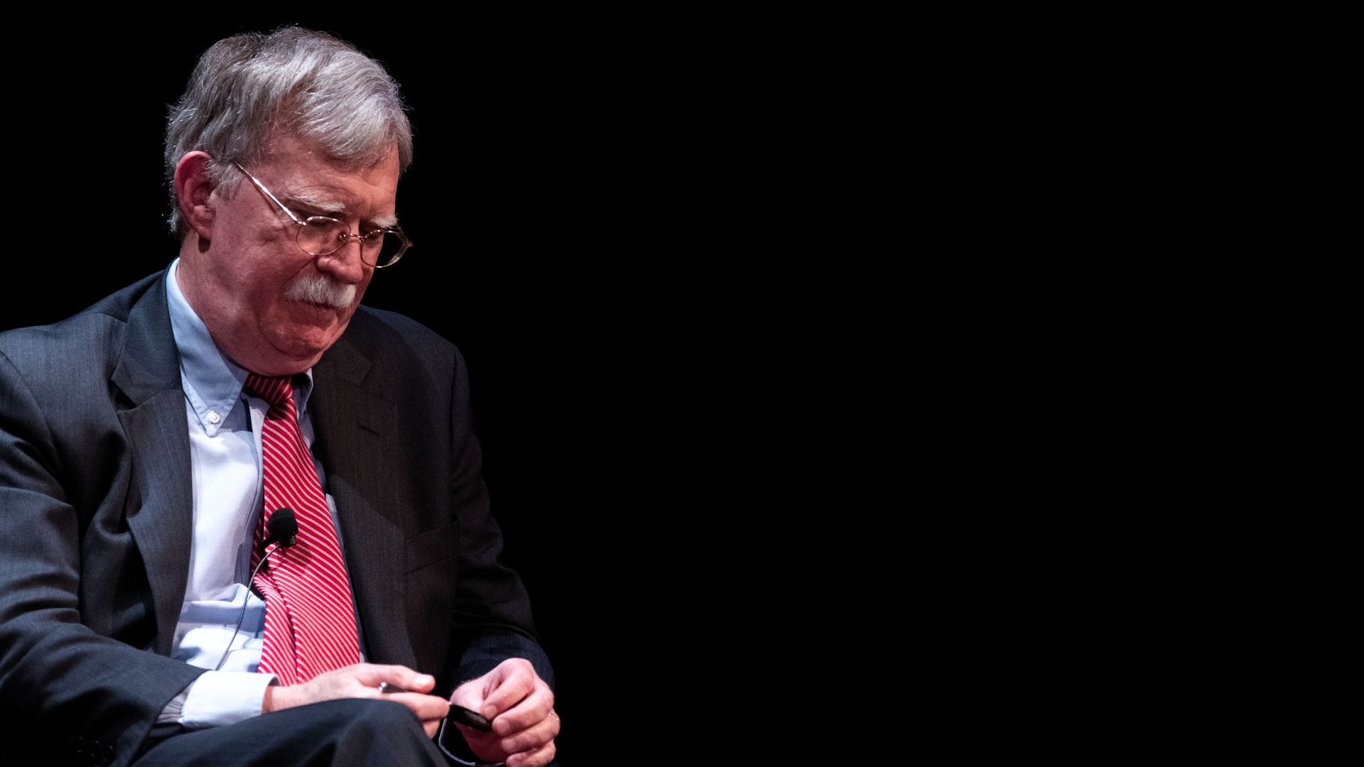 Bolton sits in a suit and tie