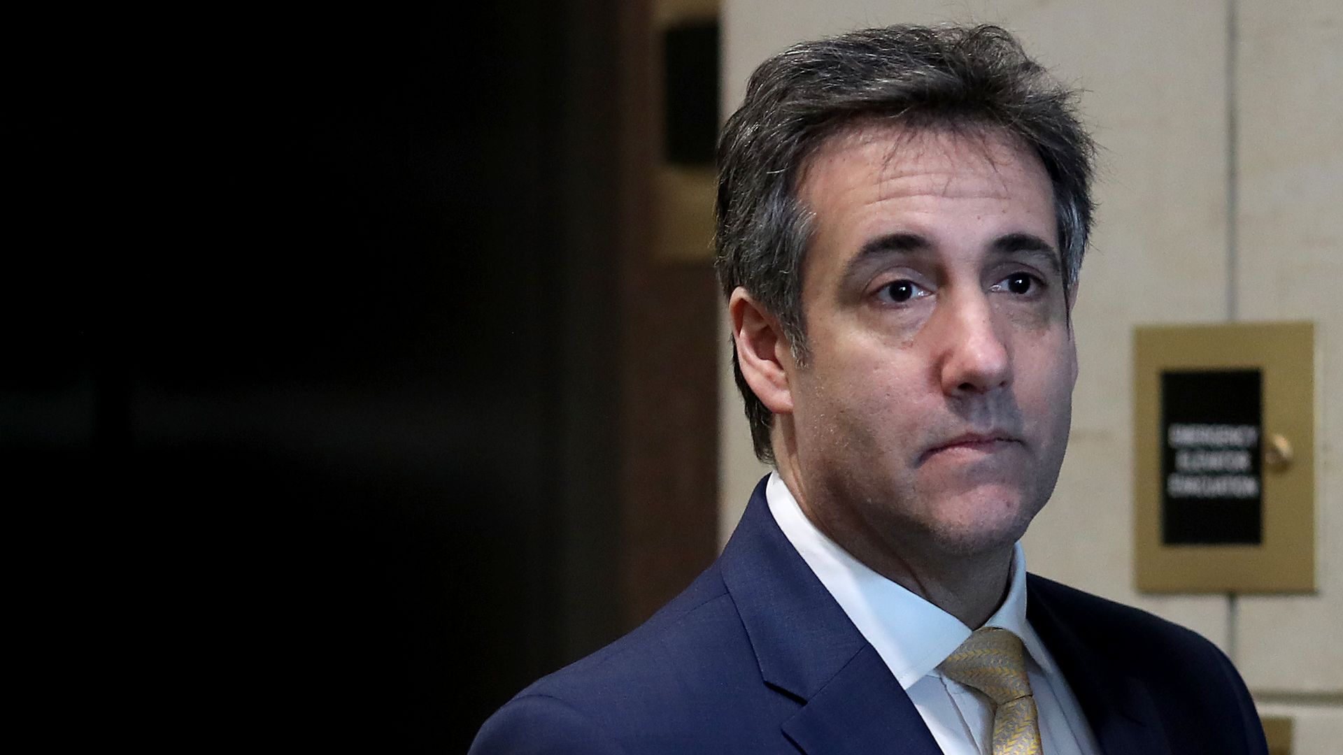 In this image, Michael Cohen stands next to an elevator. 