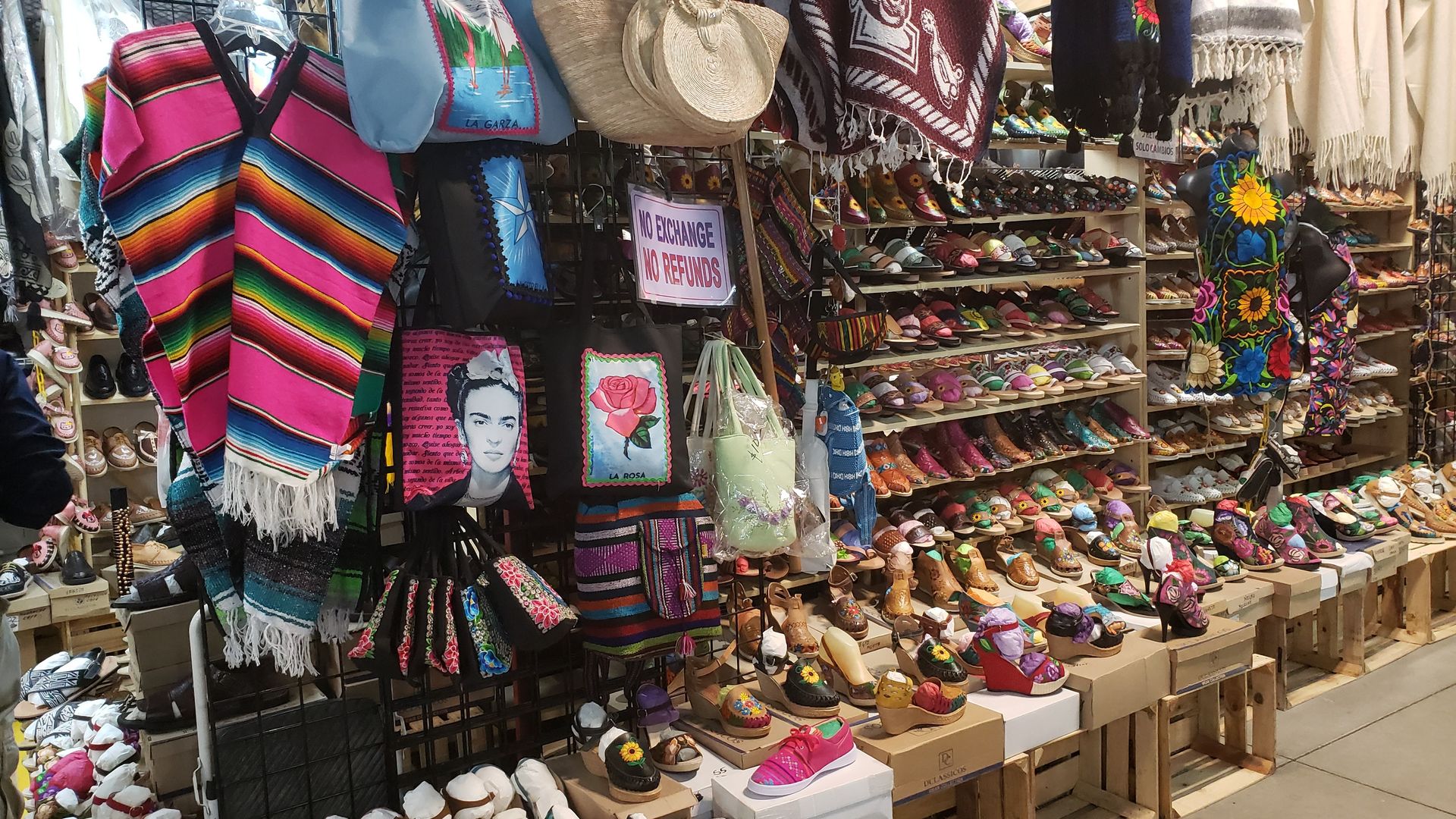 Photo of a kiosk filled with shoes, scarves, purses and paintings.