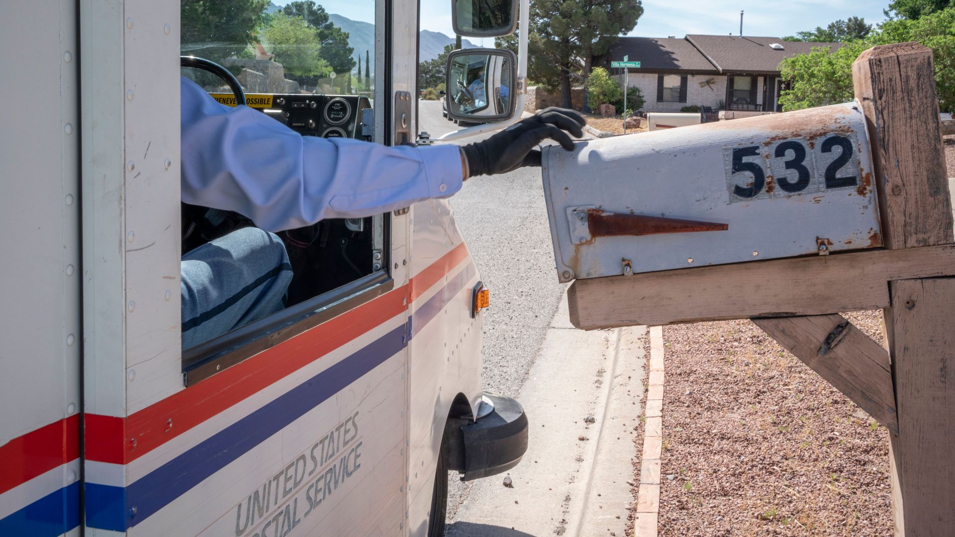 A mail carrier in United States Postal Service truck delivers mail