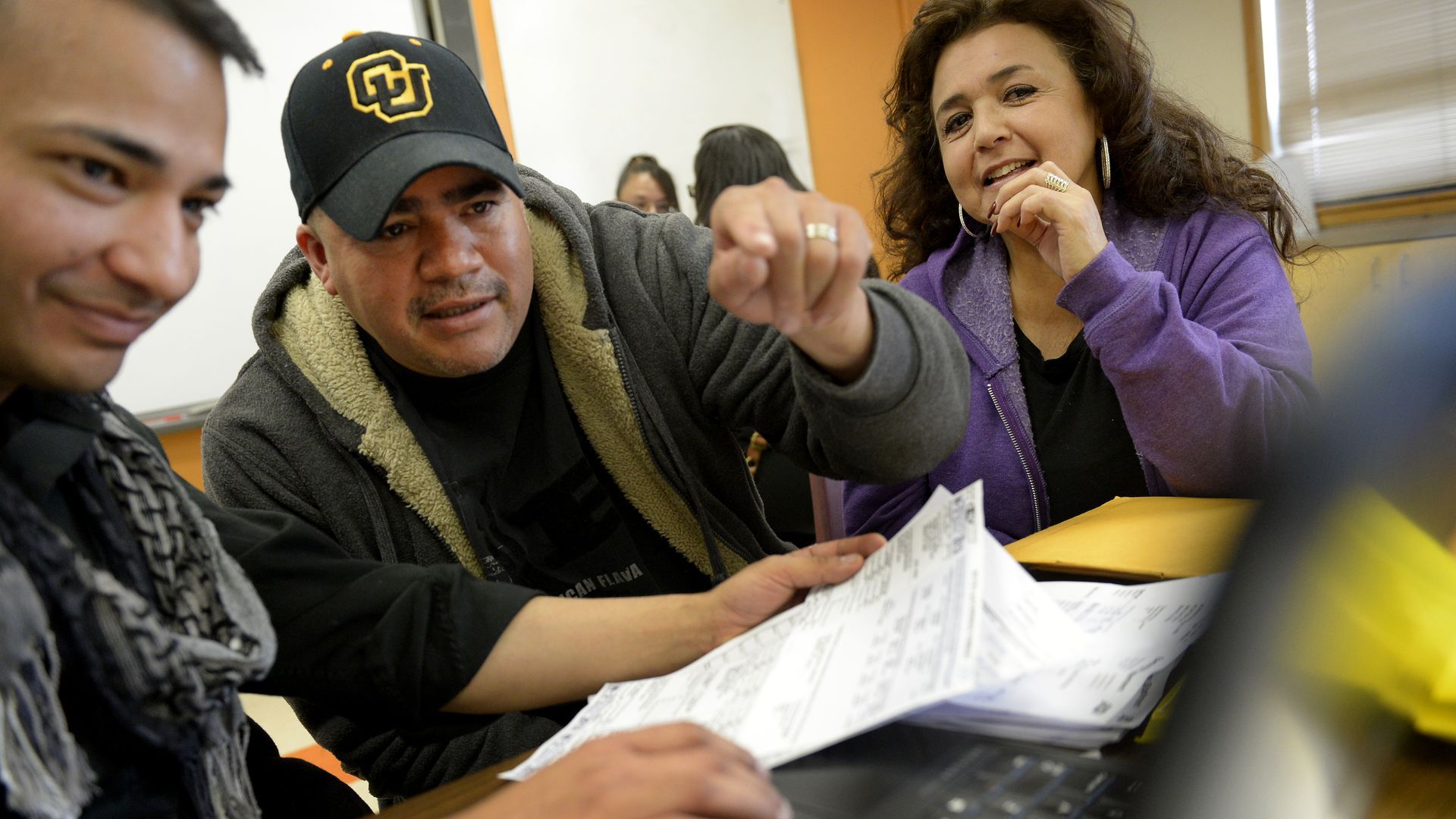 Two men, left, look over paperwork while a woman, on the right, looks over