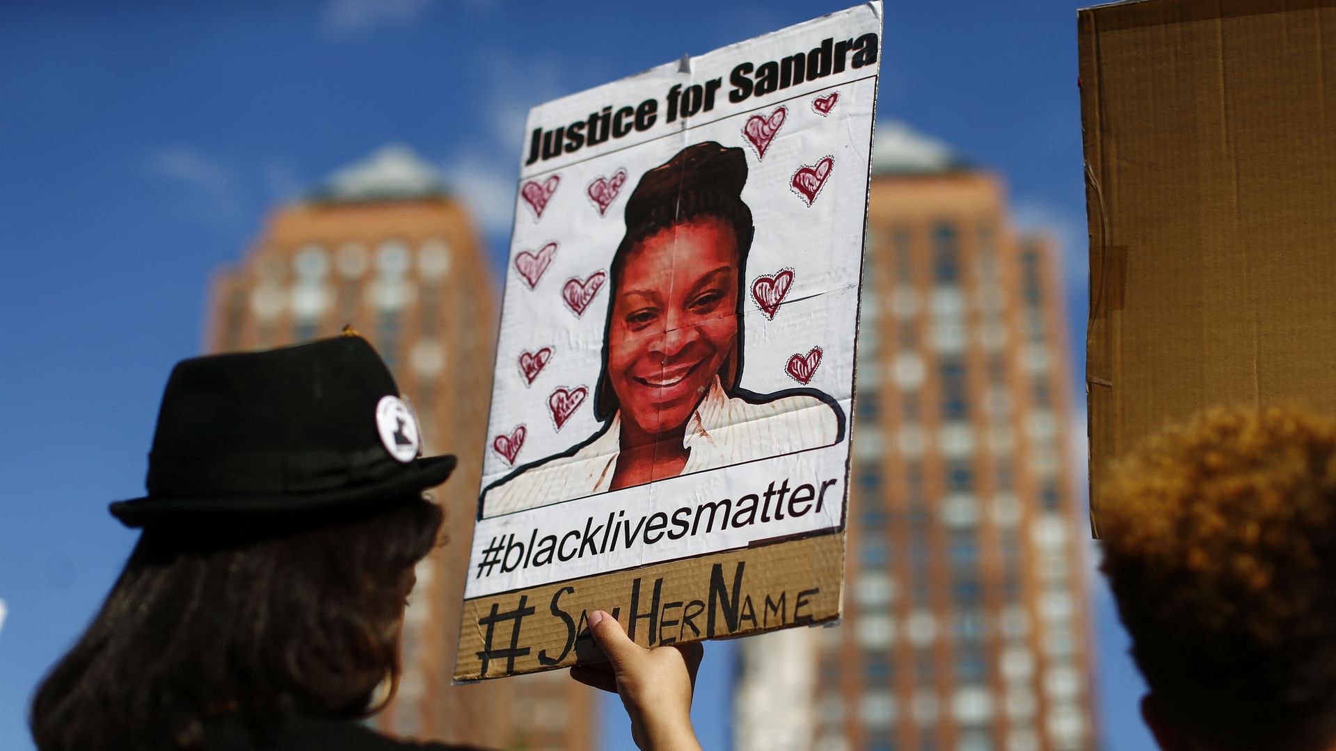 Protestor holds a portrait of Sandra Bland. 
