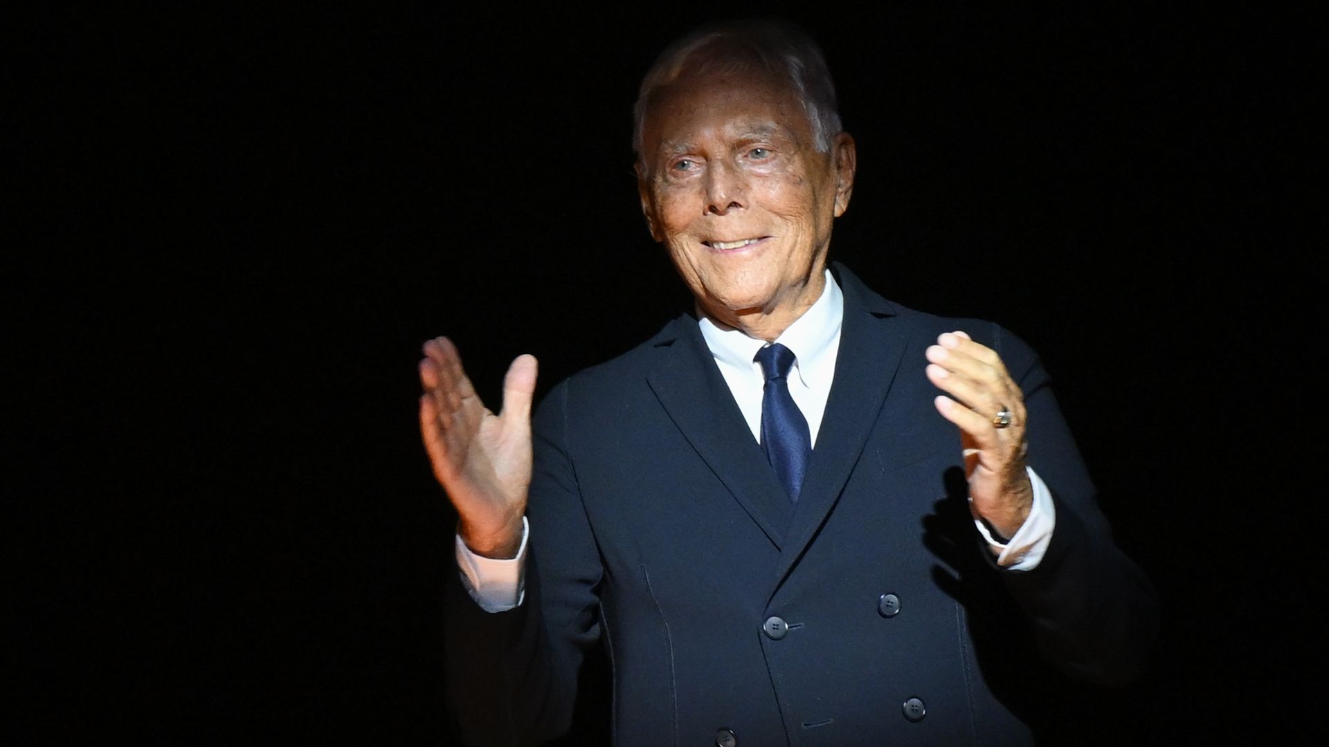 Giorgio Armani, the designer, is dressed in a dark suit.