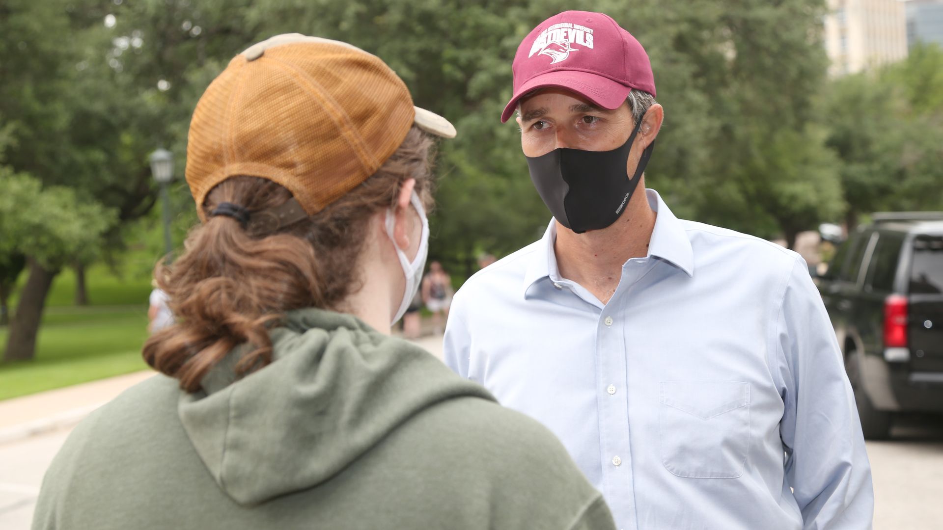 Beto O'Rourke wears a face mask and a baseball cap 