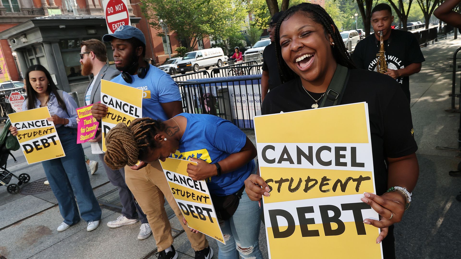 People holding signs that say "Cancel Student Debit"