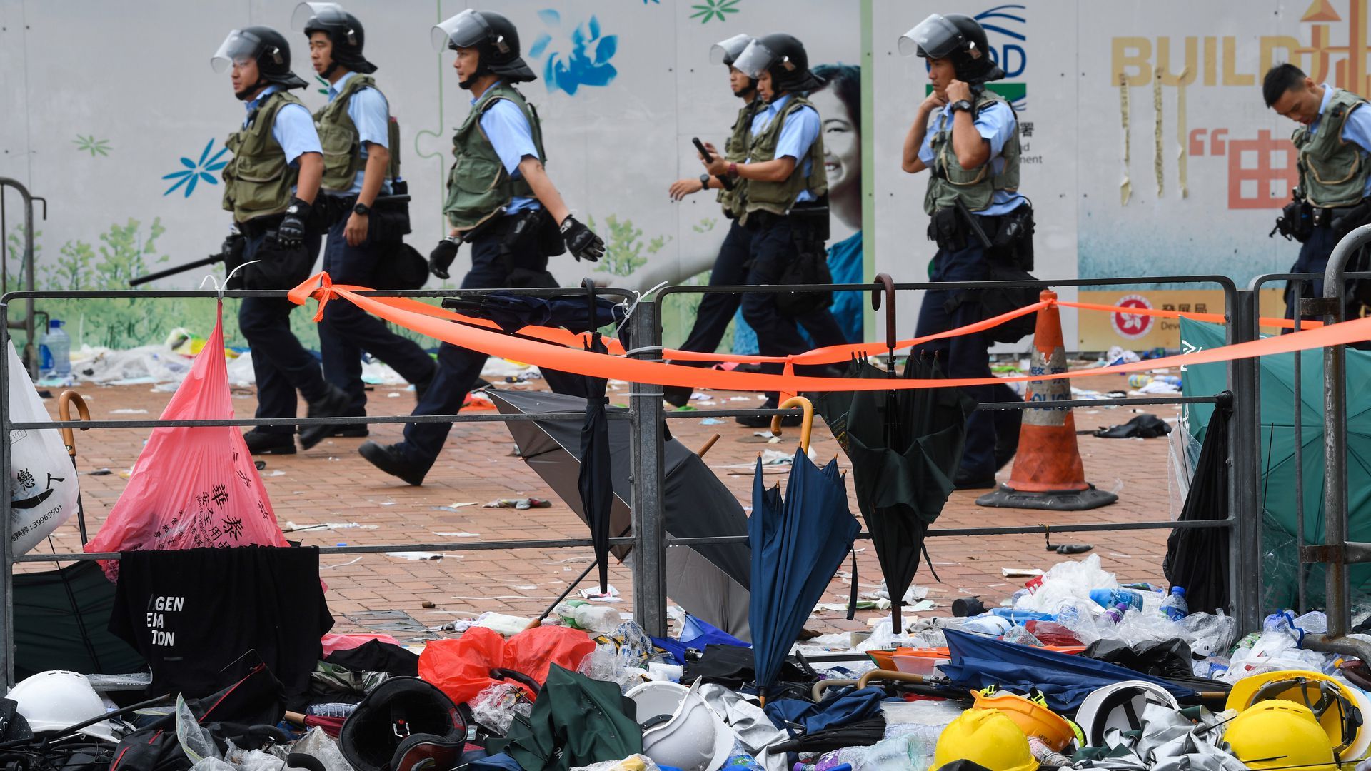 Police walk past debris on a street a day after a mass protest. Photo: Anthony Wallace/AFP/Getty Images