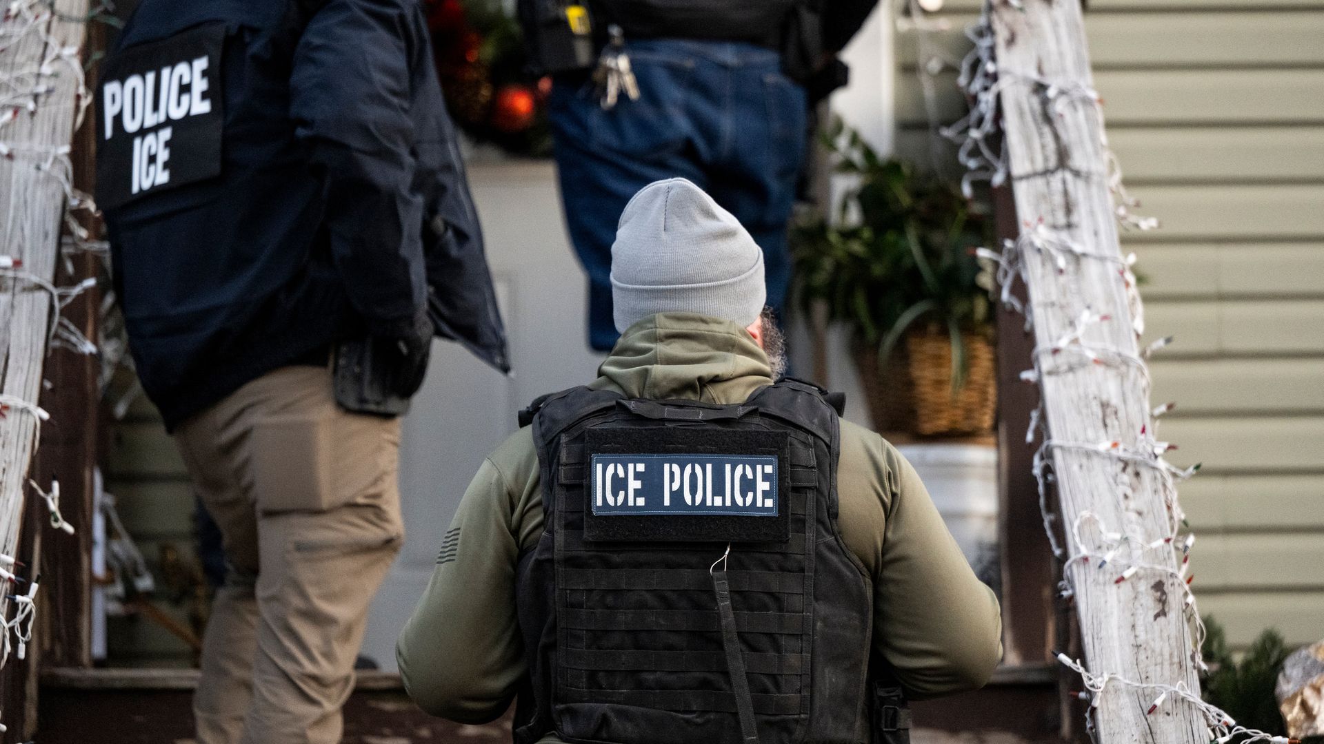 Photo of ICE agents in uniform approaching a front door