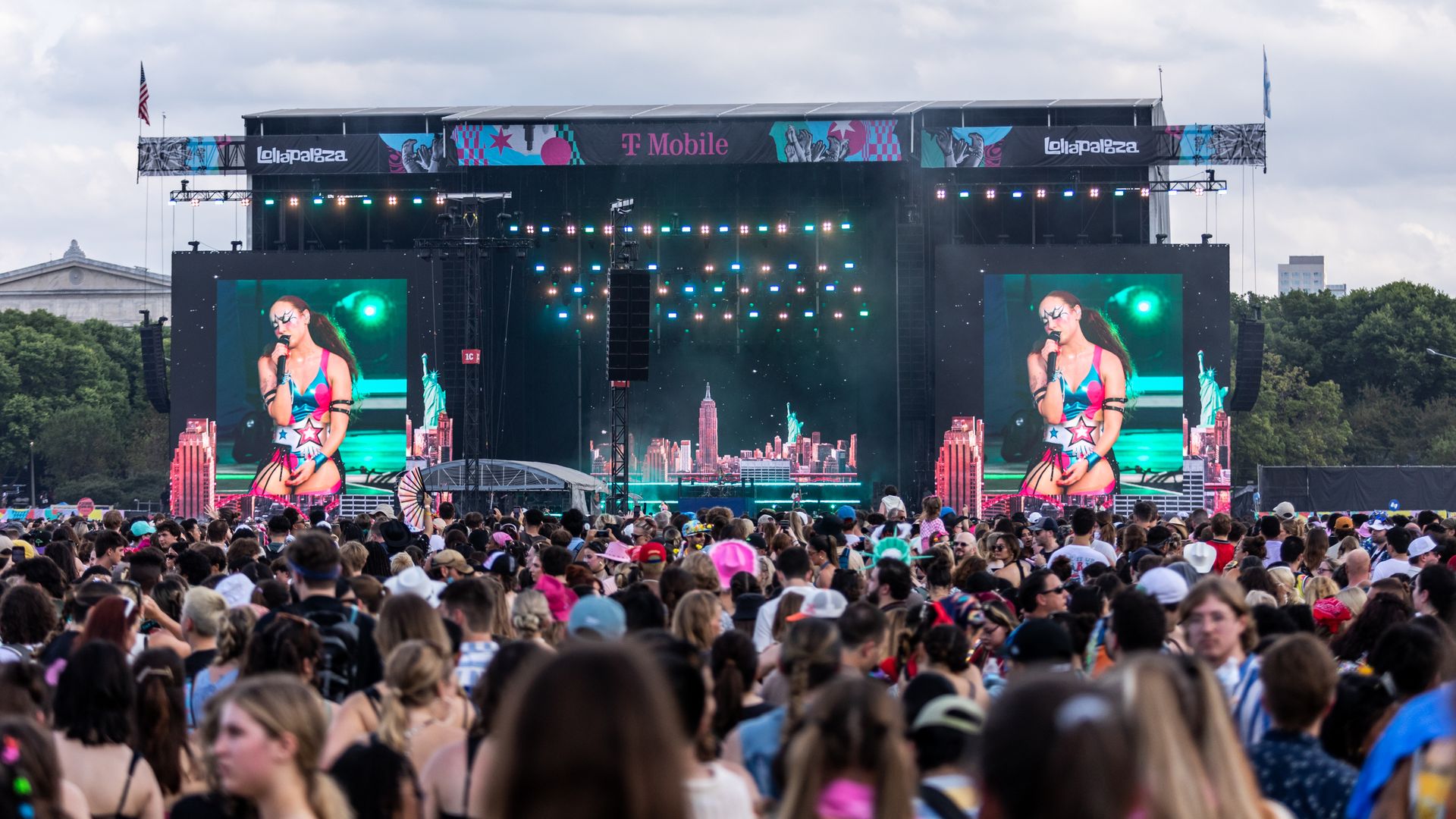 Photo of a crowd watching a musician on big screens next to a stage