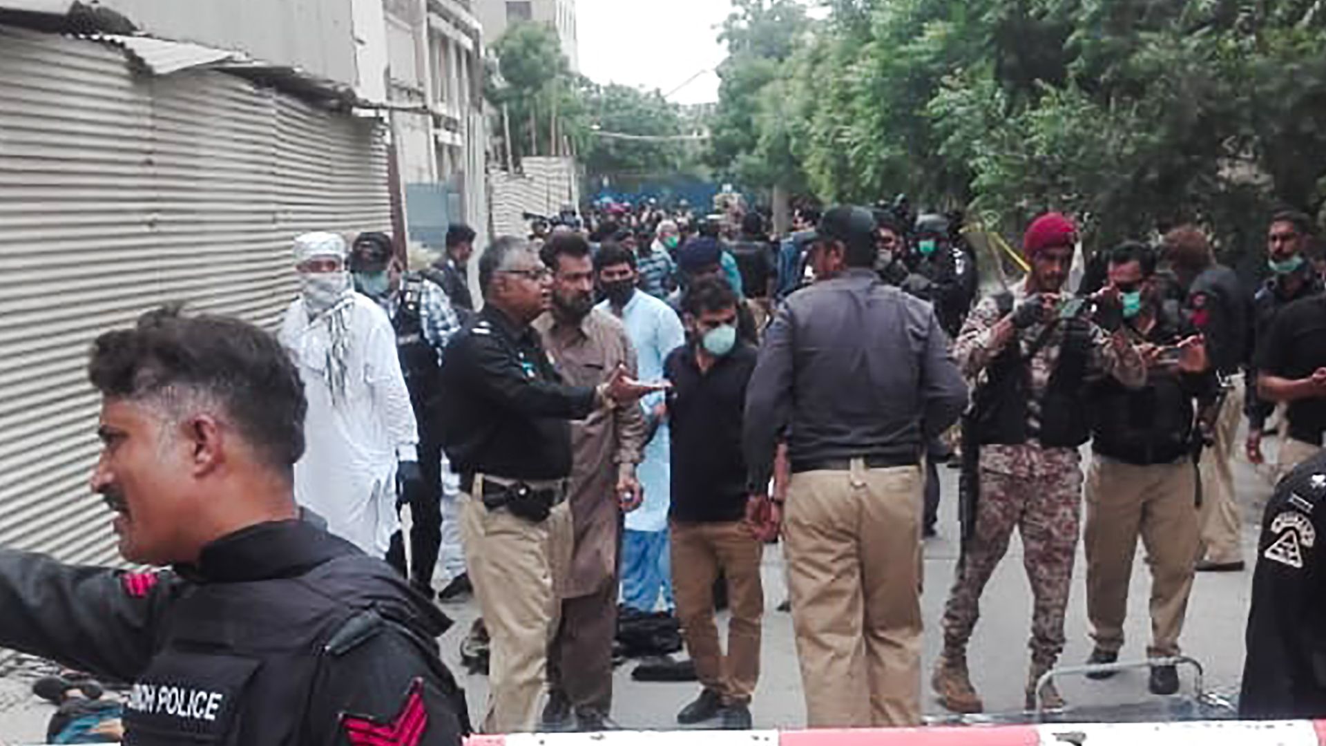 Policemen secure an area around a body outside the Pakistan Stock Exchange building after a group of gunmen attacked the building in Karachi on June 29