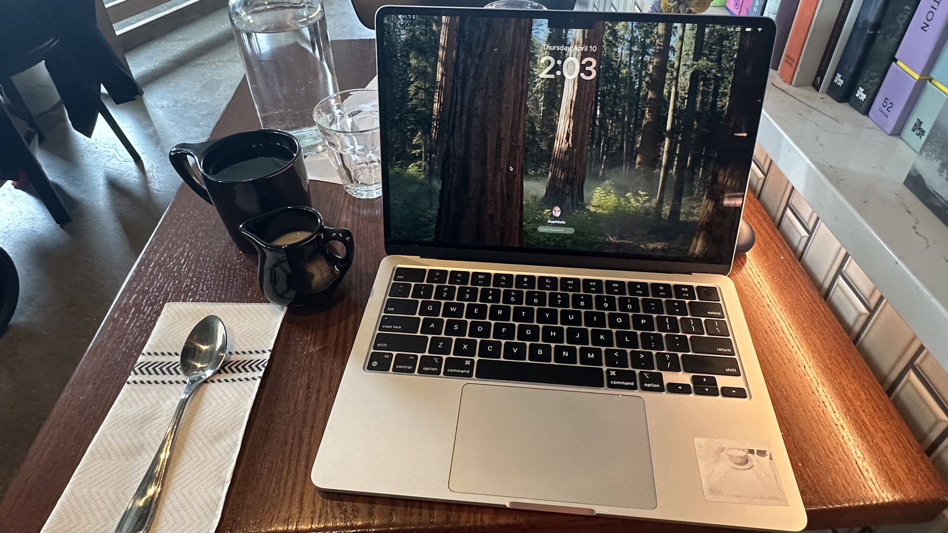 A laptop and coffee with a glass of cream at a table at Shy Bird in South Boston.