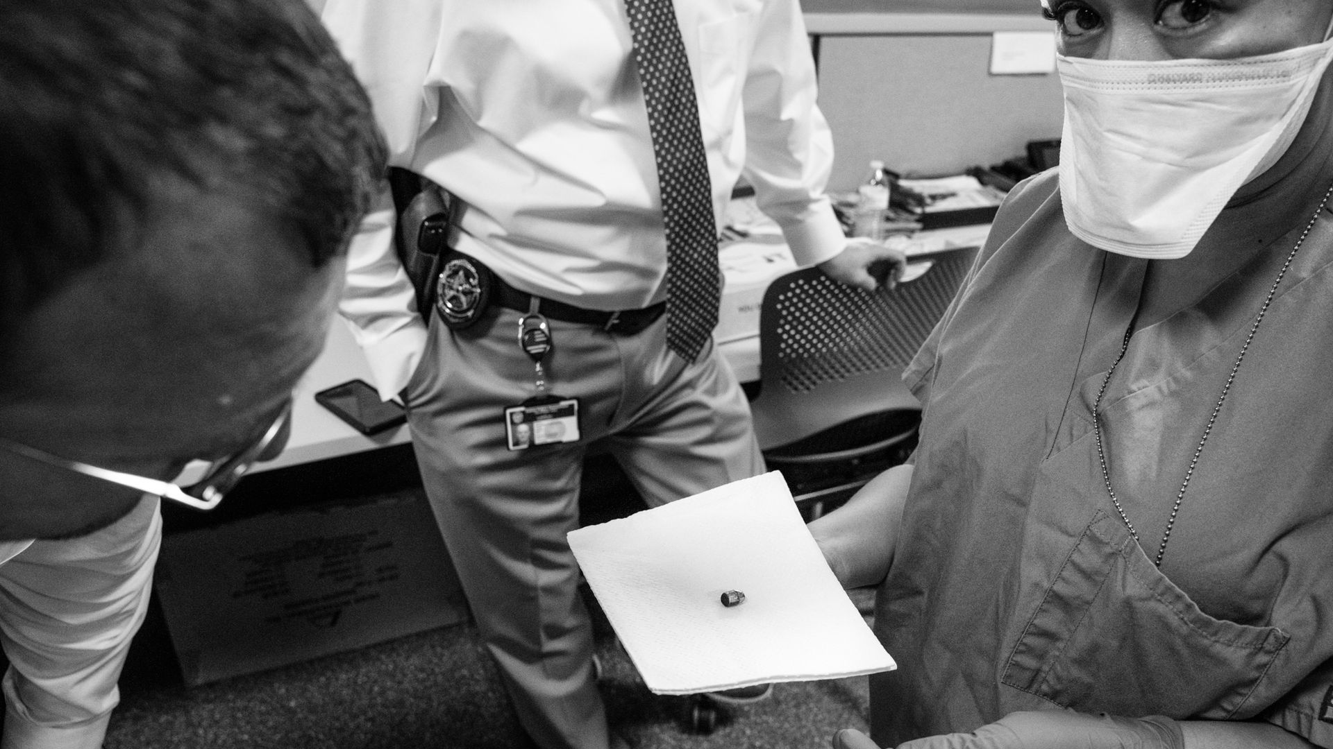 A person holds a bullet on a white piece of paper