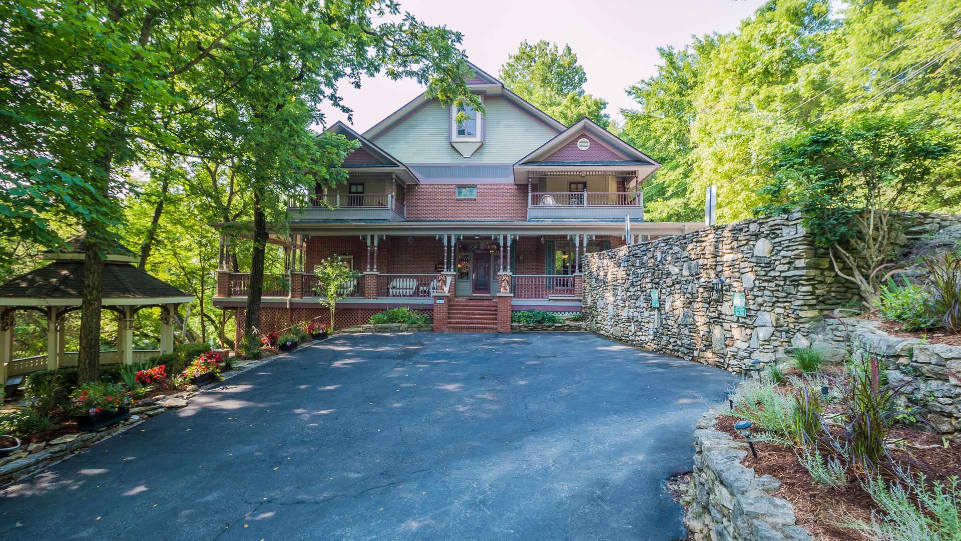 Photo of a green and red brick Victorian-style bed and breakfast in the woods. 