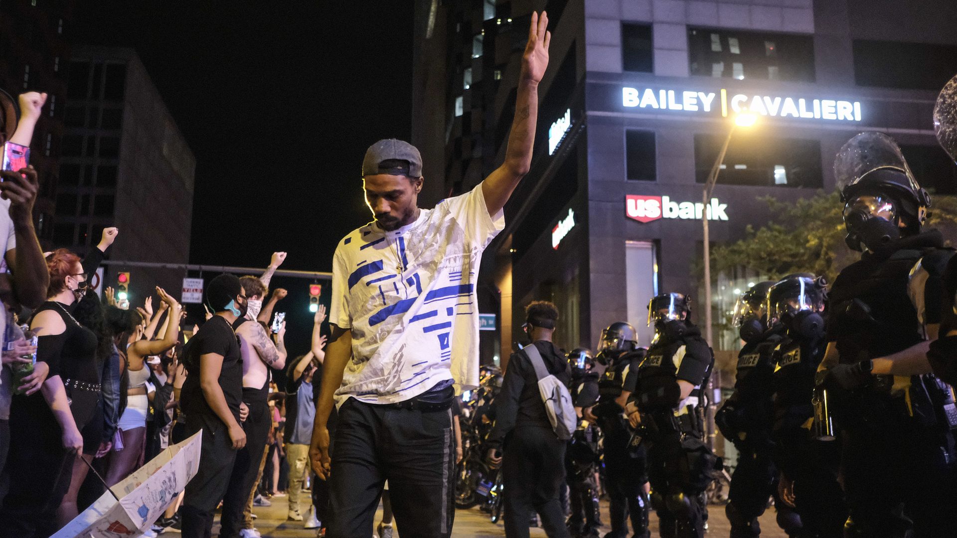 A man holds his hand up between protesters and police during the 2020 George Floyd protests in Columbus