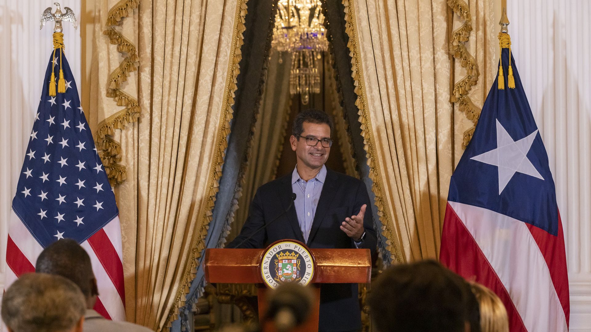 Puerto Rico's governor Pedro Pierluisi stands next to a Puerto Rican flag and US flag