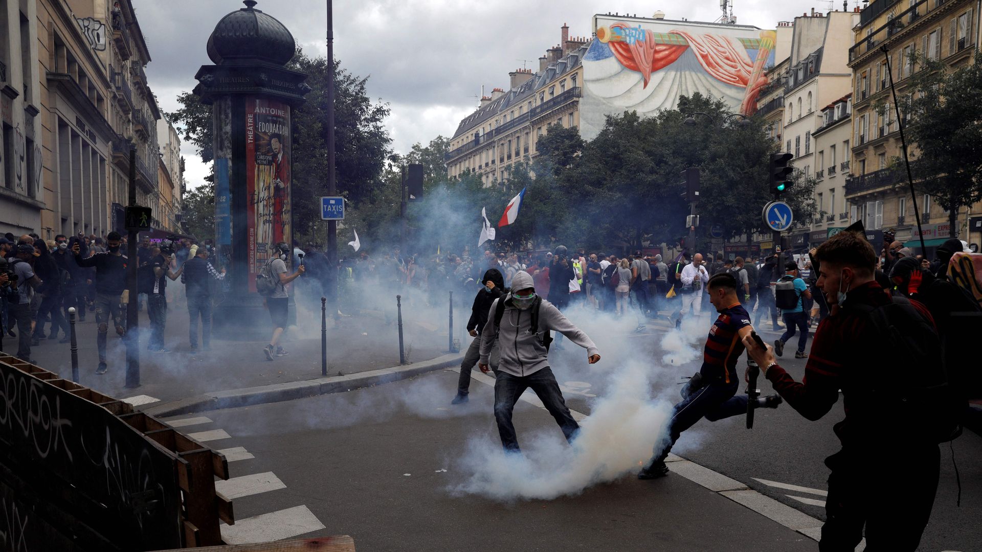 A protester kicks a smoking teargas shell during a demonstration in Paris on July 31 against new pandemic measures