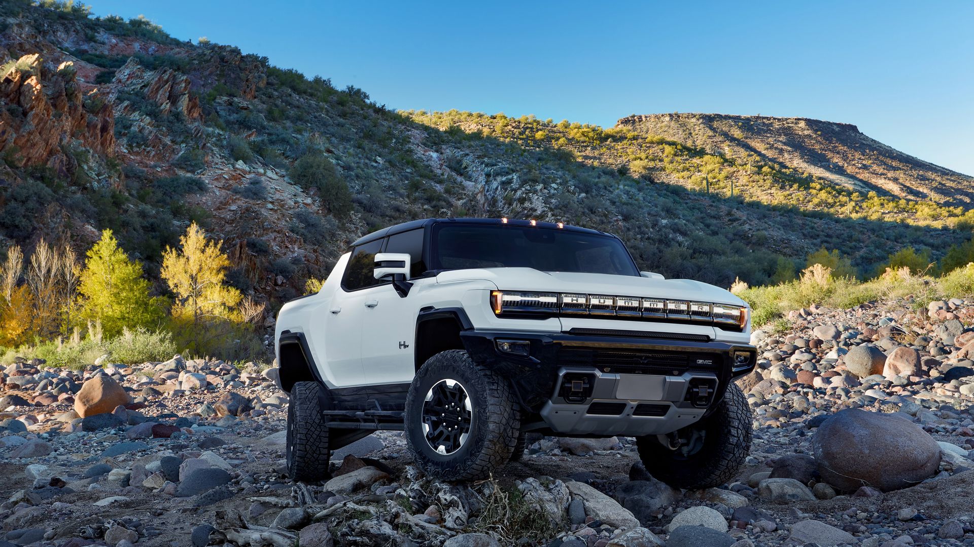 Image of a white GMC Hummer EV pickup truck with four-wheel steering, showing both the front and rear wheels turning in the same direction - a function known as "crabwalk"