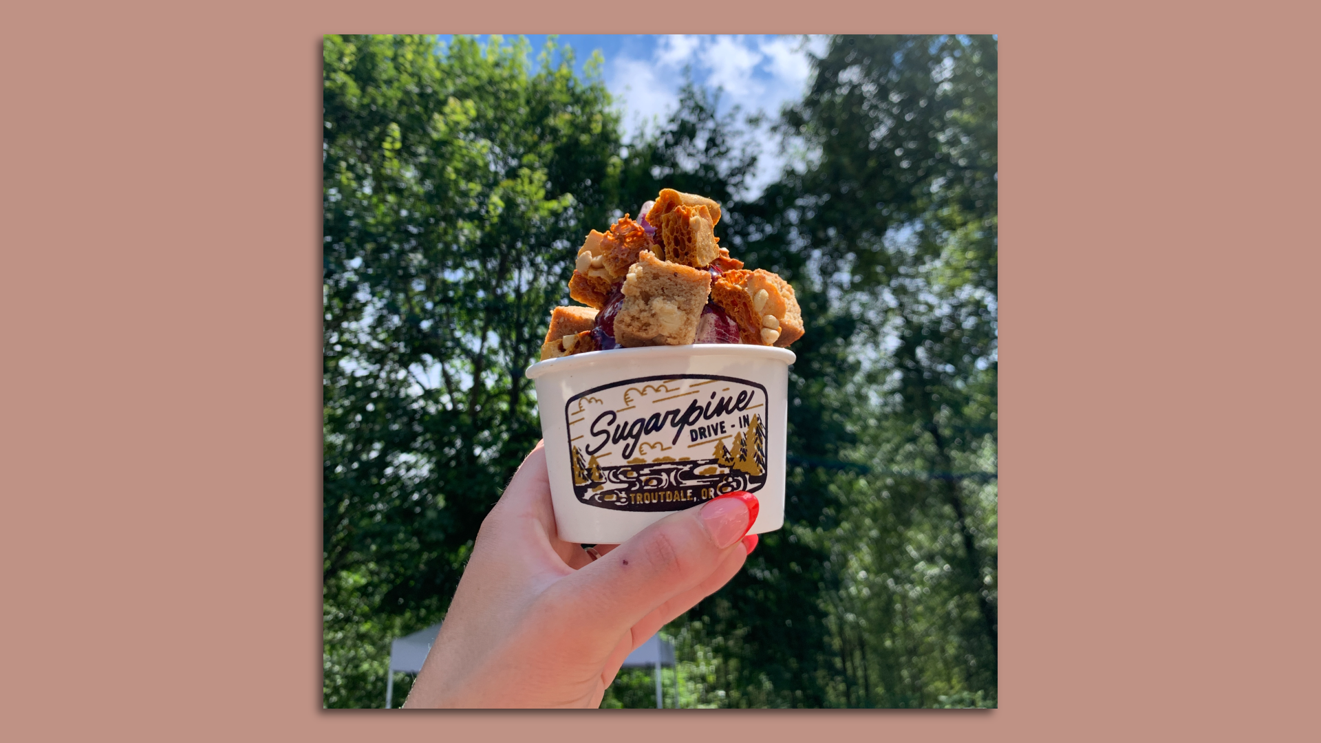 A photo of a hand holding a cup full of soft serve.