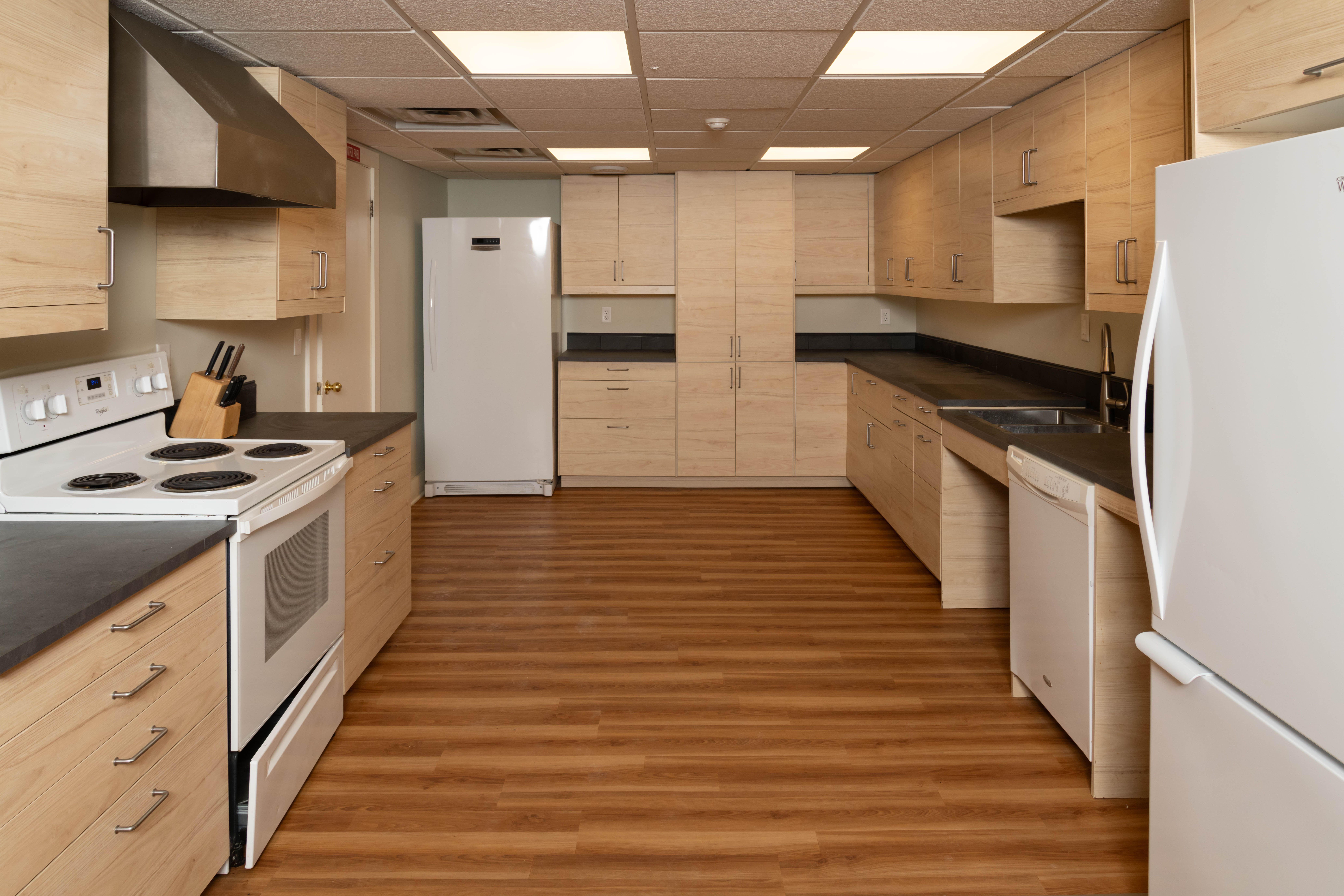 A commercial kitchen with light wood cabinets.