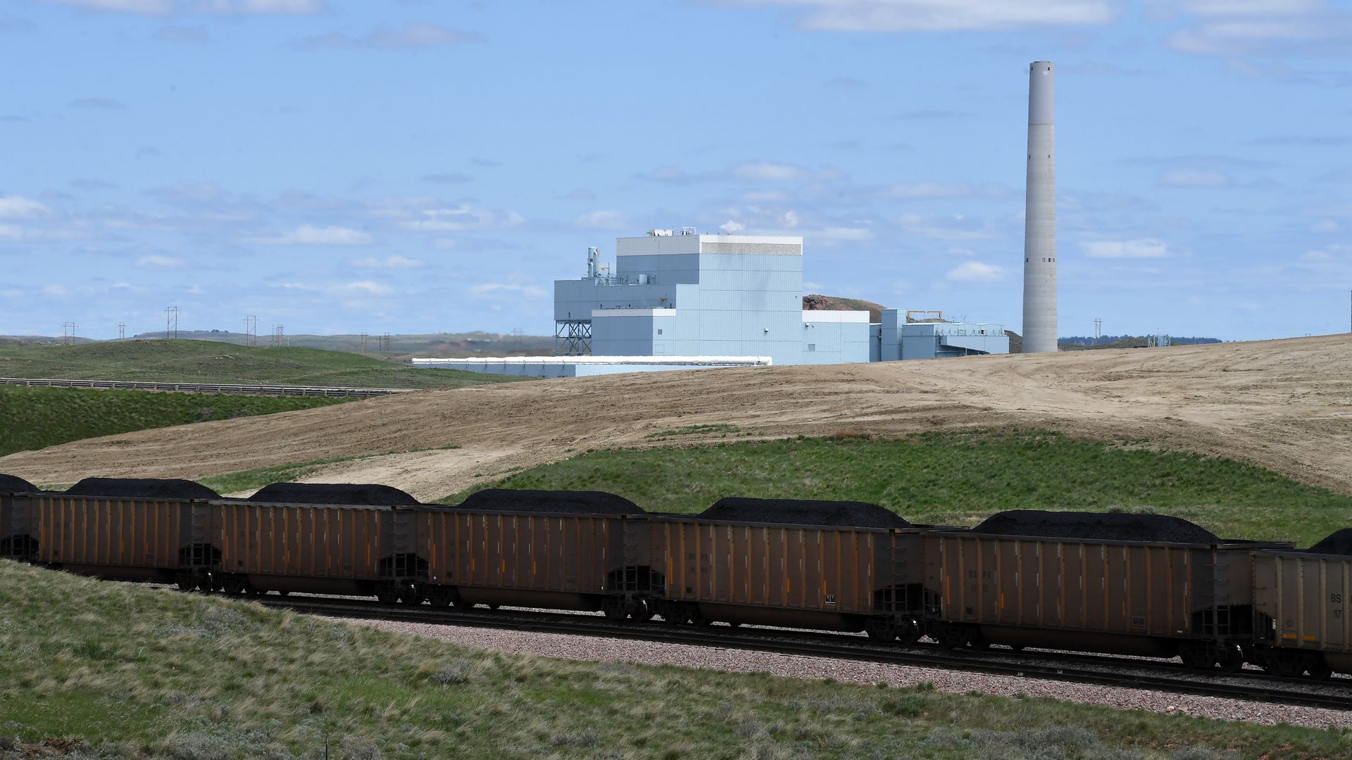 A coal train in front of a coal fired power plant.