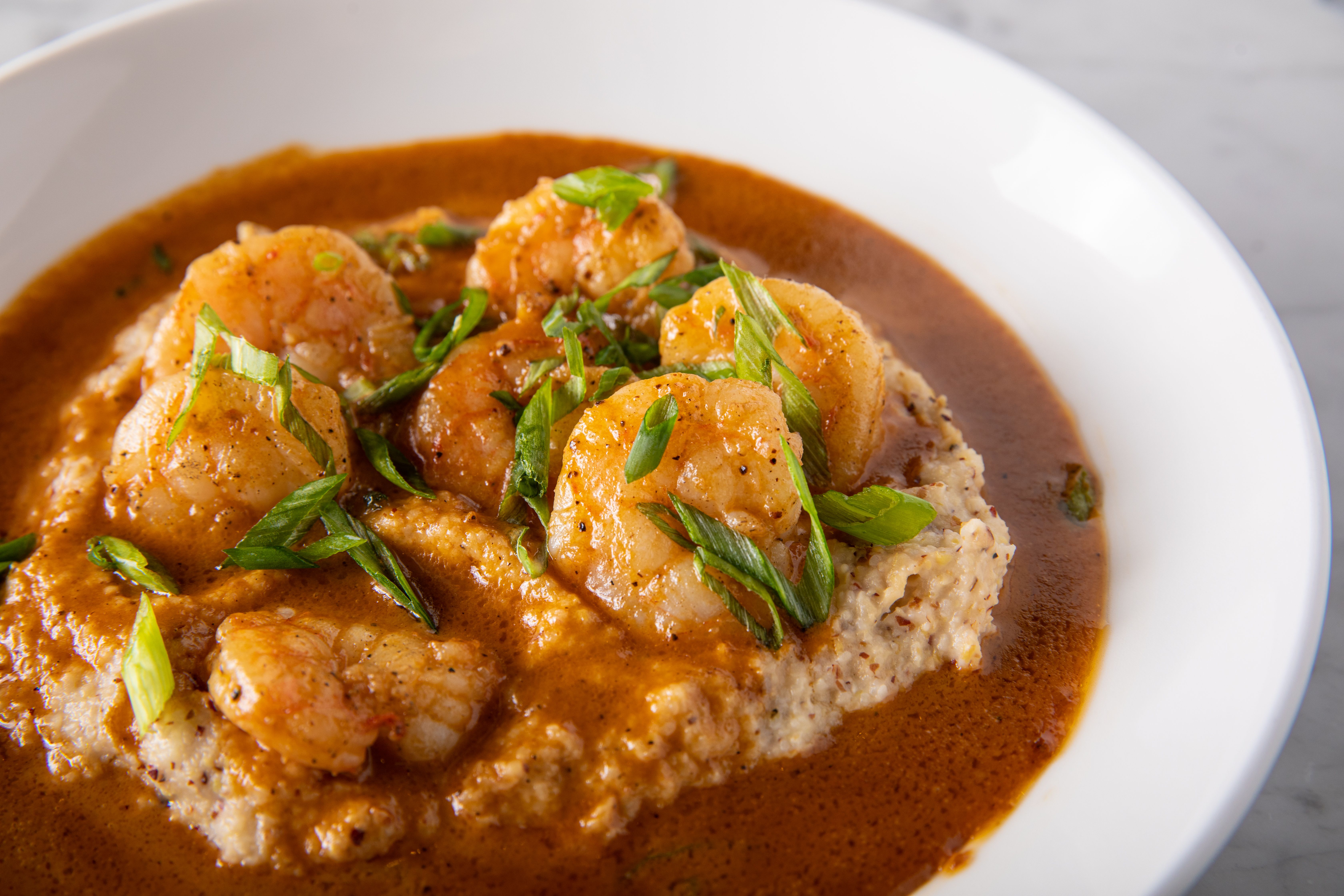 Image shows shrimp and grits in a white bowl.