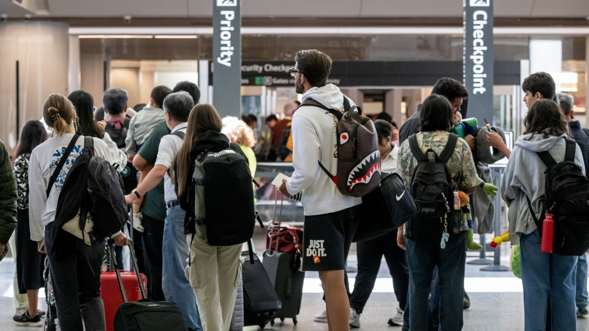 A group of travelers wait in line at the airport security checkpoint.