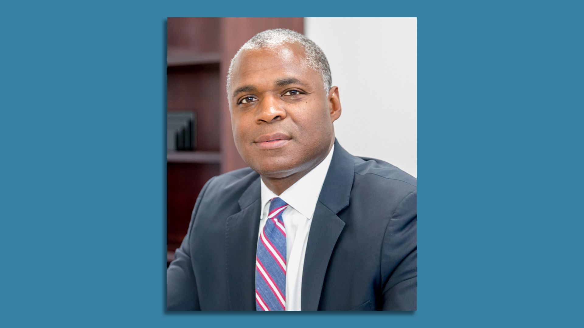 A headshot of Collie Greenwood wearing a coat and tie