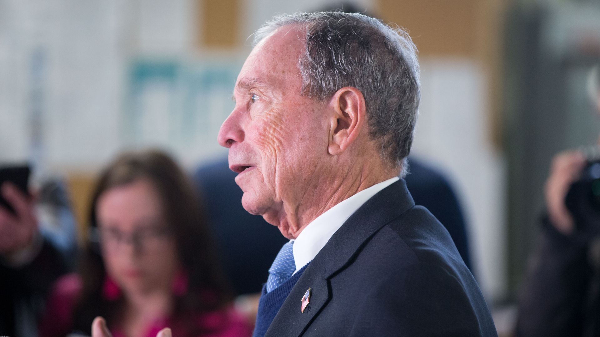 This image a side profile of Bloomberg talking and wearing a suit.