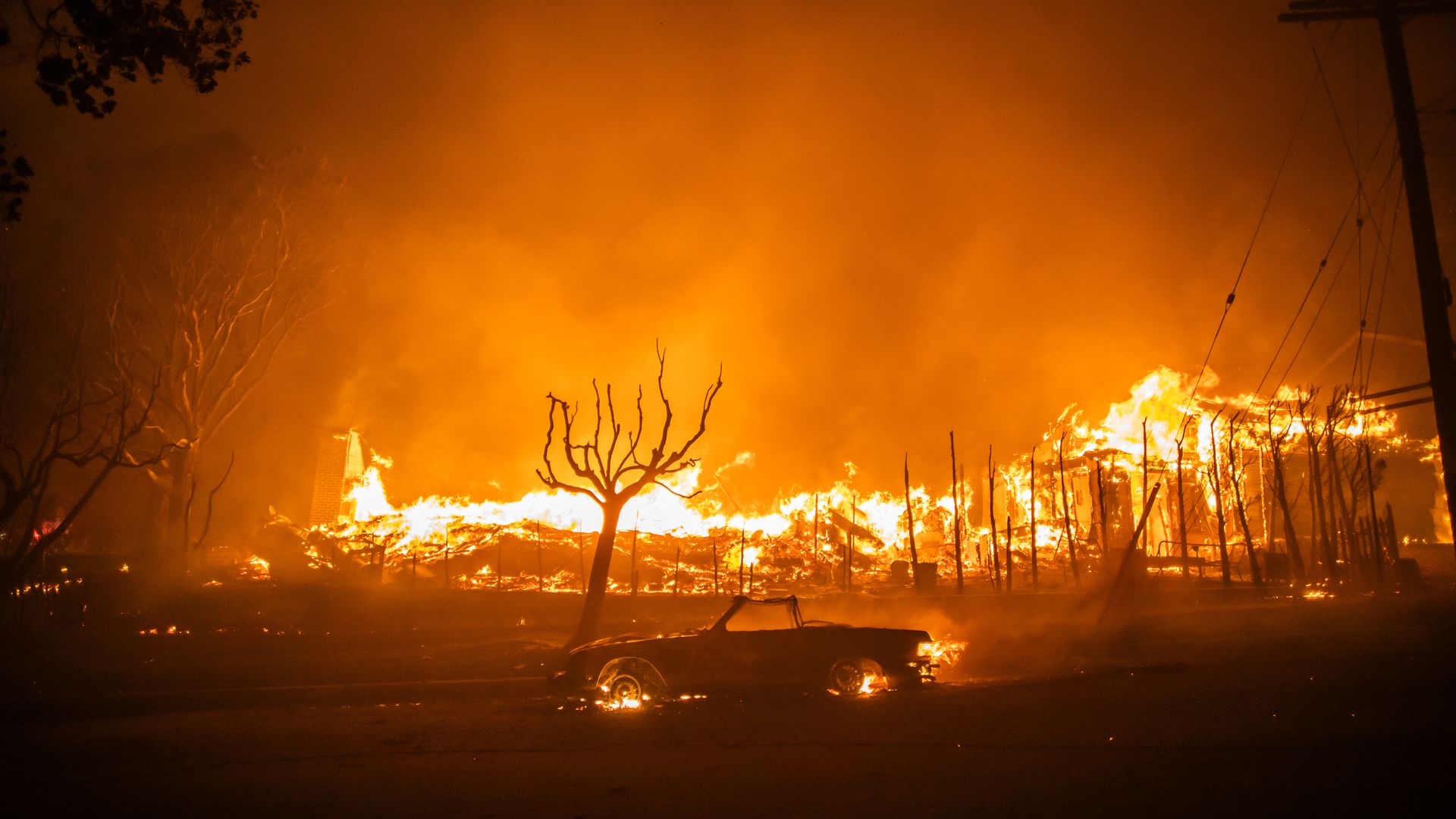 Photo of homes burning along with a car in the Palisades Fire in California.