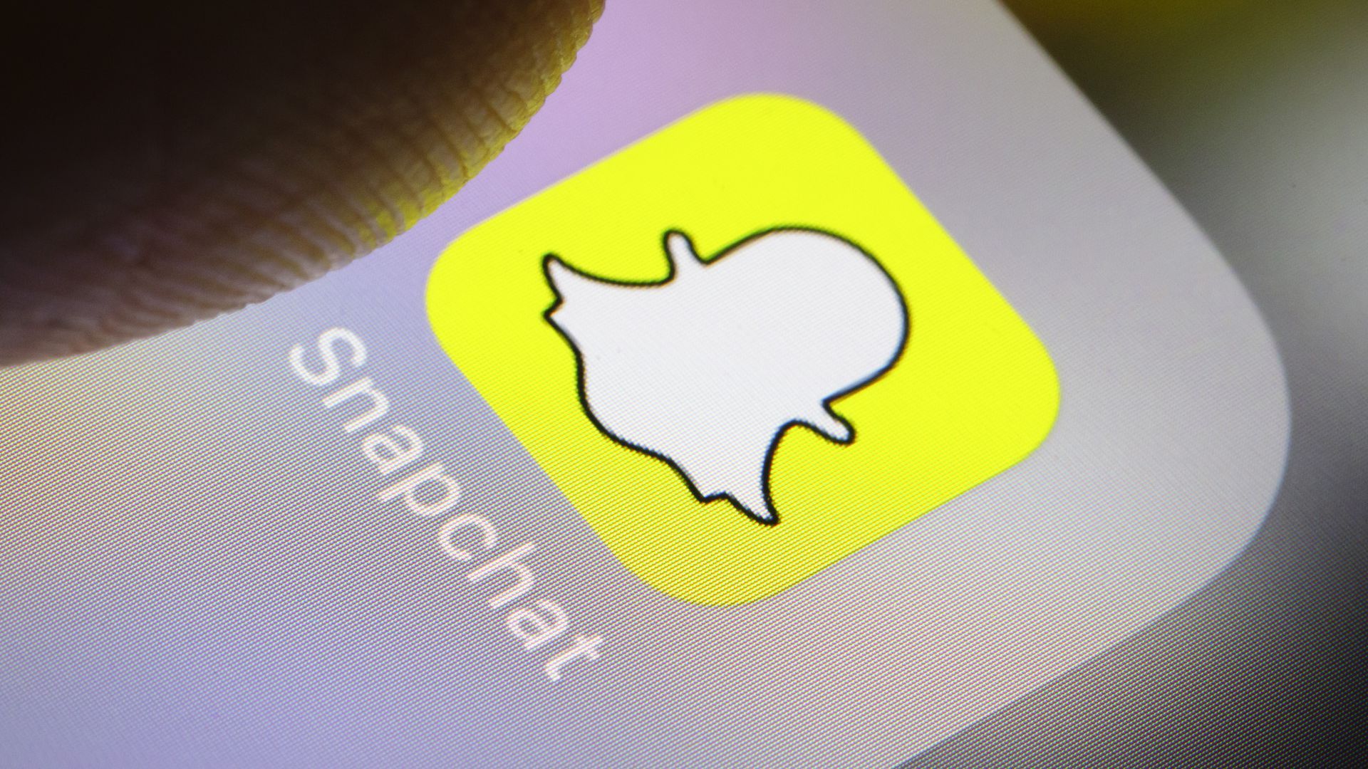 Closeup of thumb on Snapchat icon on phone