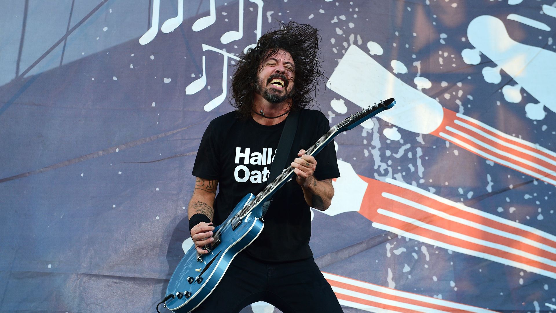 Foo Fighters' Dave Grohl plays away on his blue electric guitar while on stage.