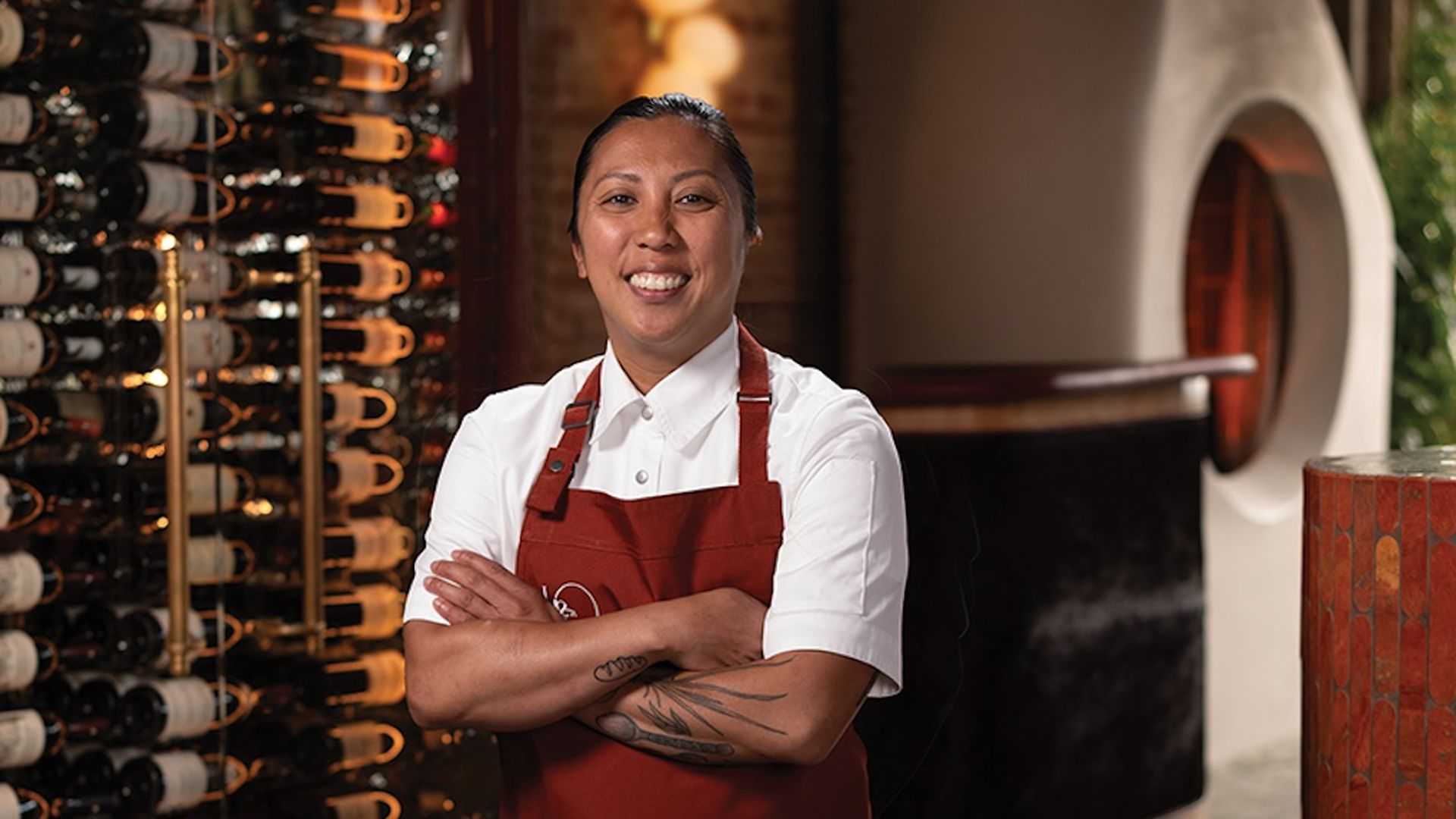 Chef Tara Monsod stands in front of a wine rack inside the restaurant Le Coq.