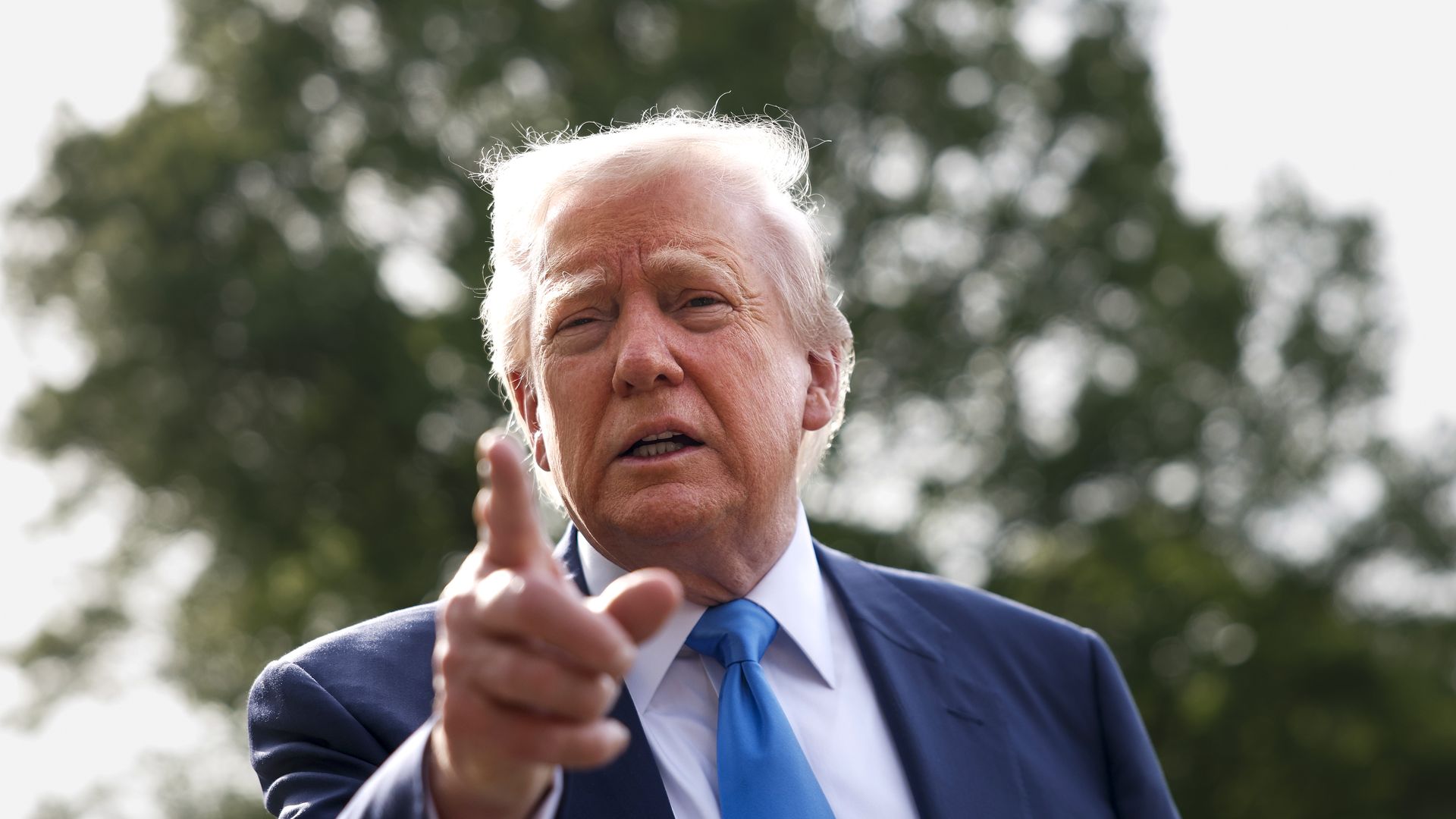 President Trump, dressed in a suit, points a finger at someone.