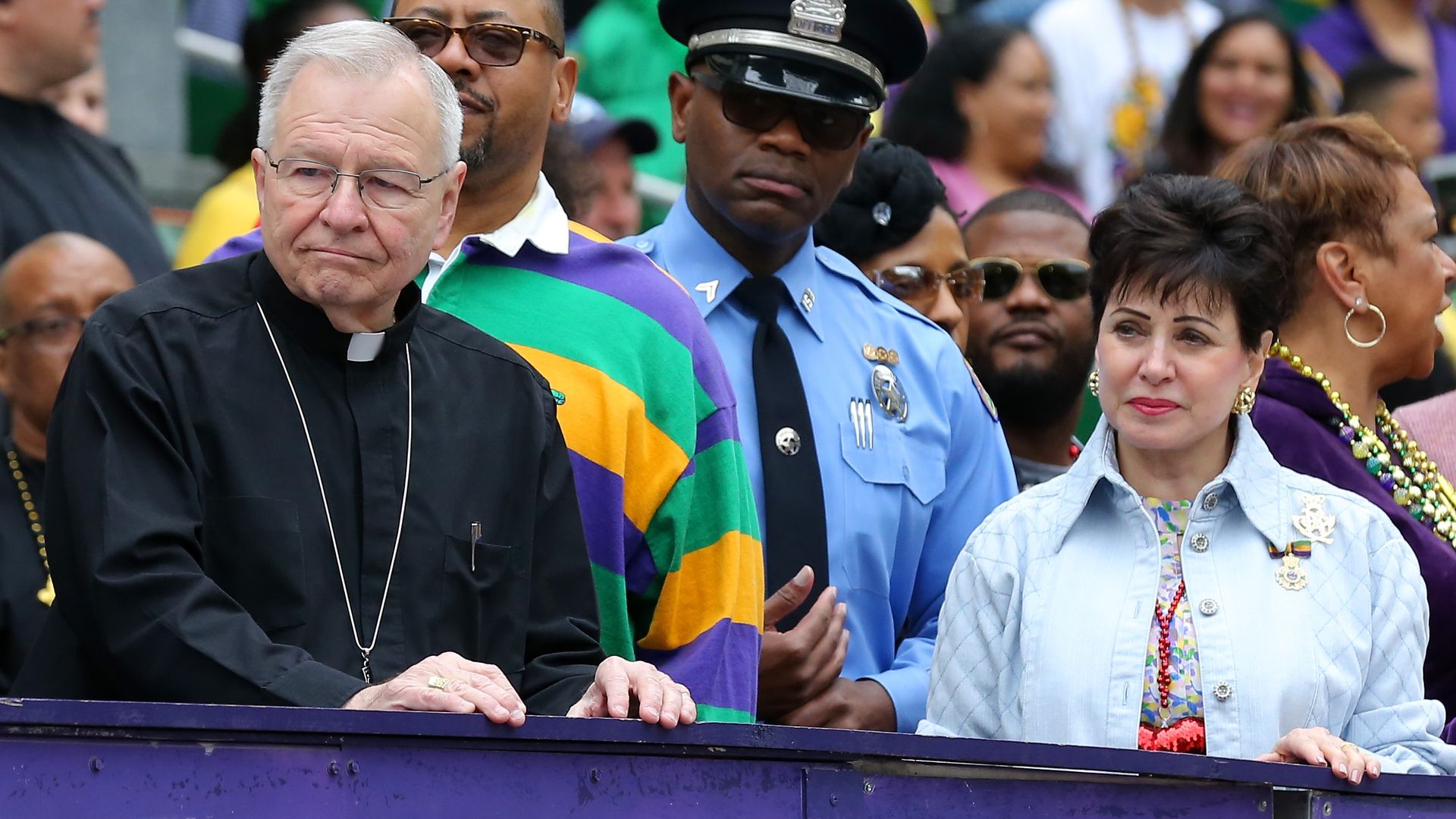 Gregory Michael Aymond, Archbishop of New Orleans, watches a parade from a viewing stand with Gayle Benson.
