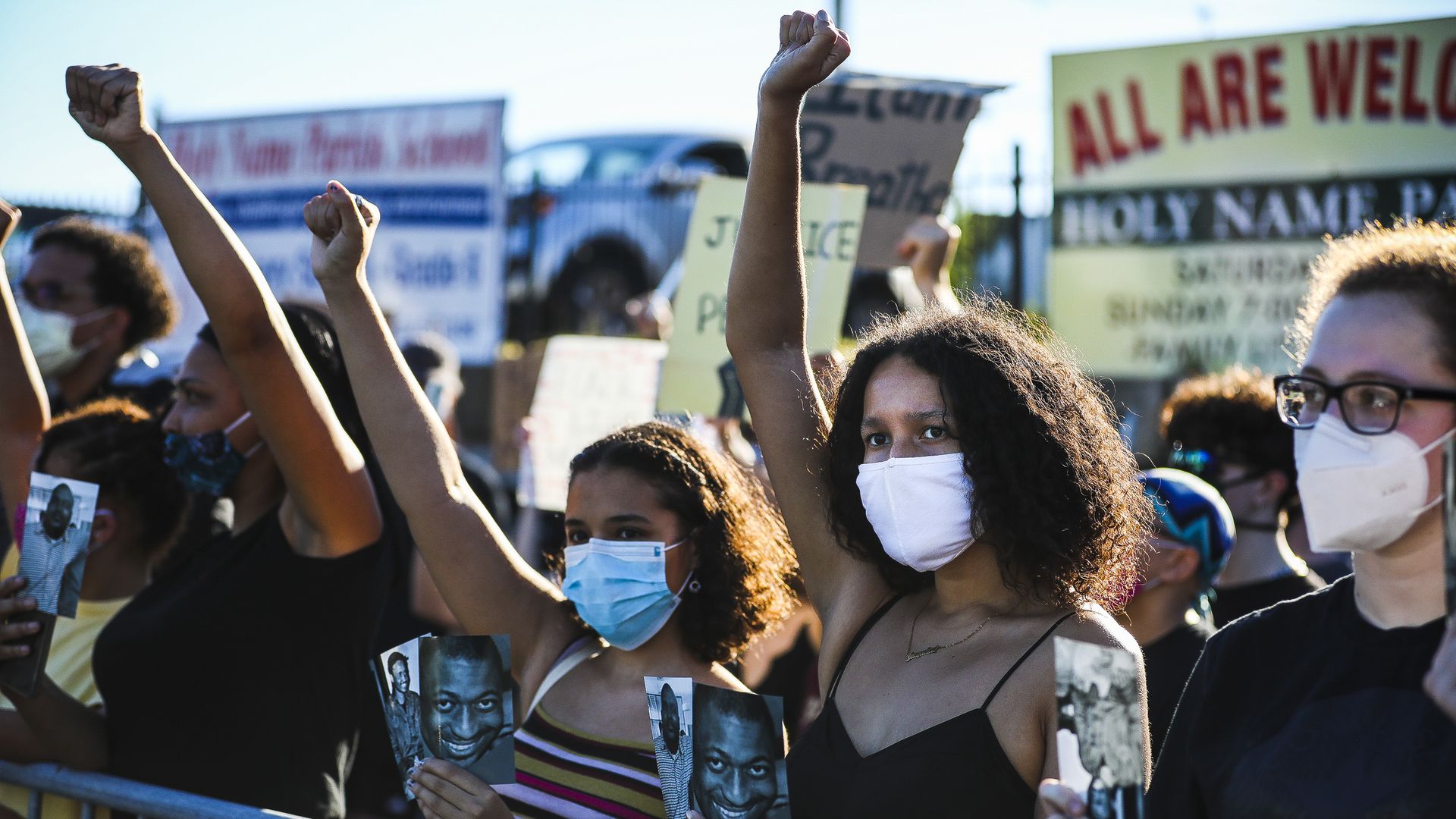Protesters stand with raised fists outside a metal fence