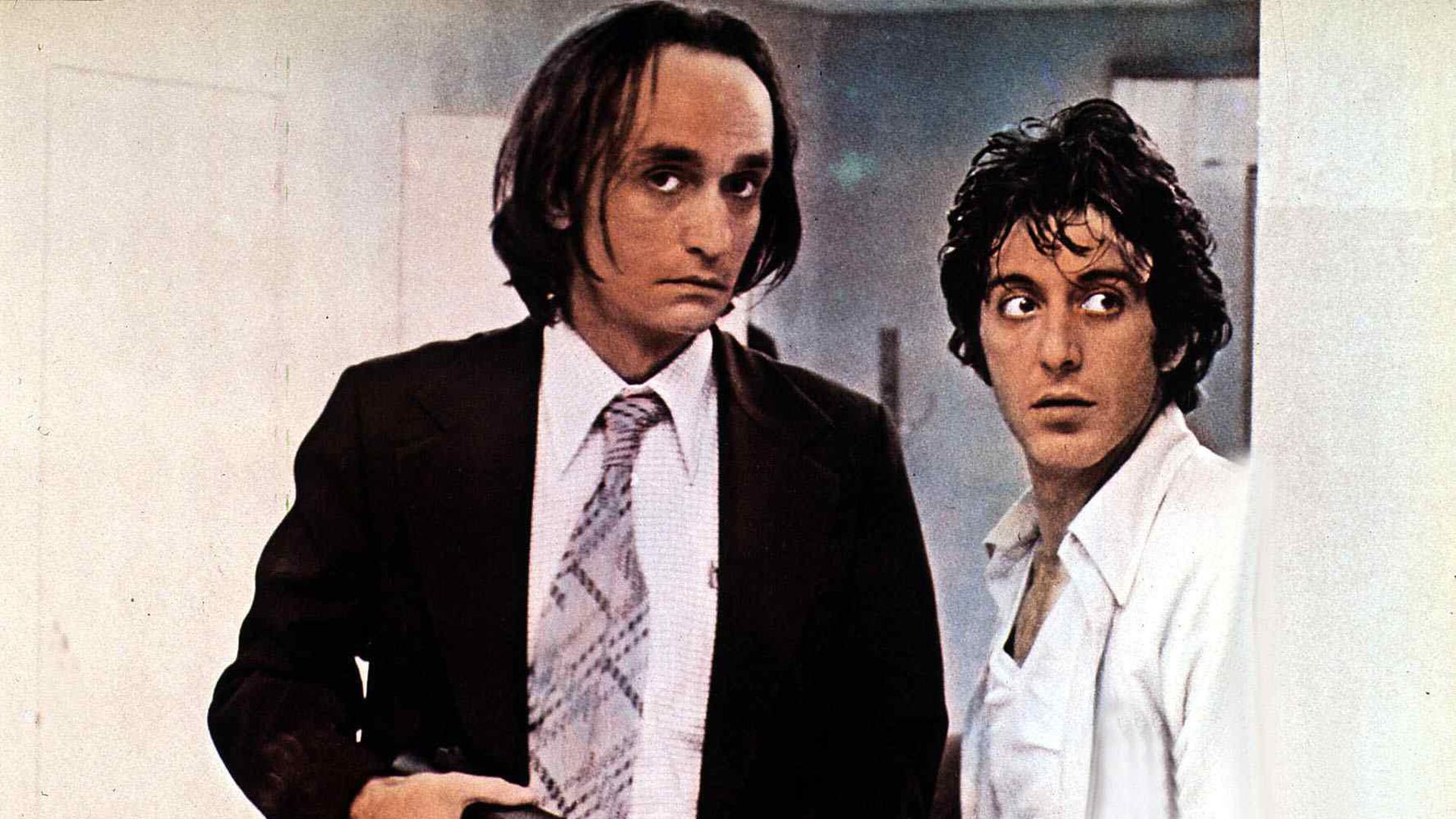 Two actors, one holding a gun, in a publicity still from a film. 