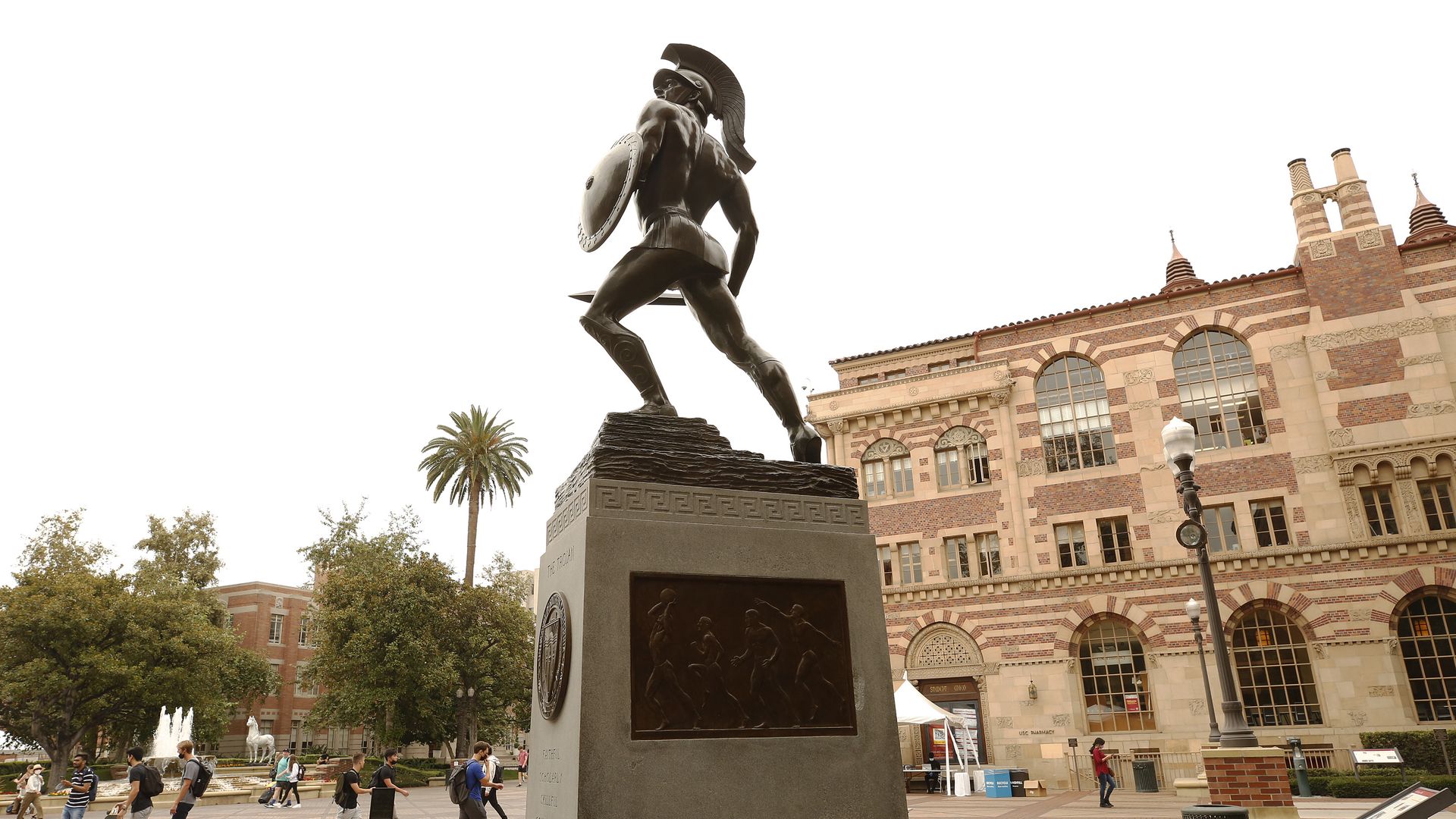 Photo of the Trojan statue in the center of the USC campus with students walking around