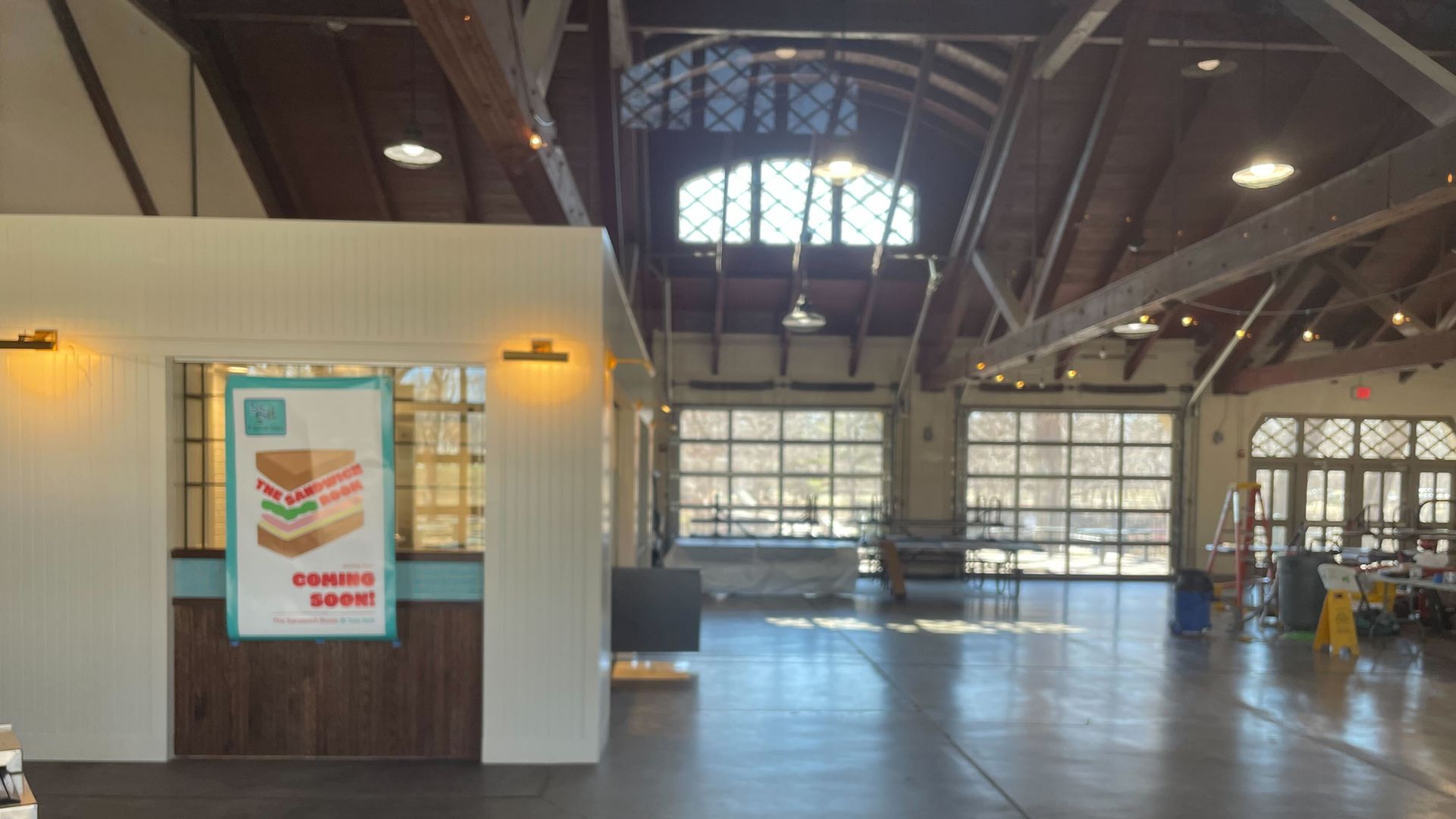 a view inside a pavilion with a white sandwich shop with a sign that says opening soon