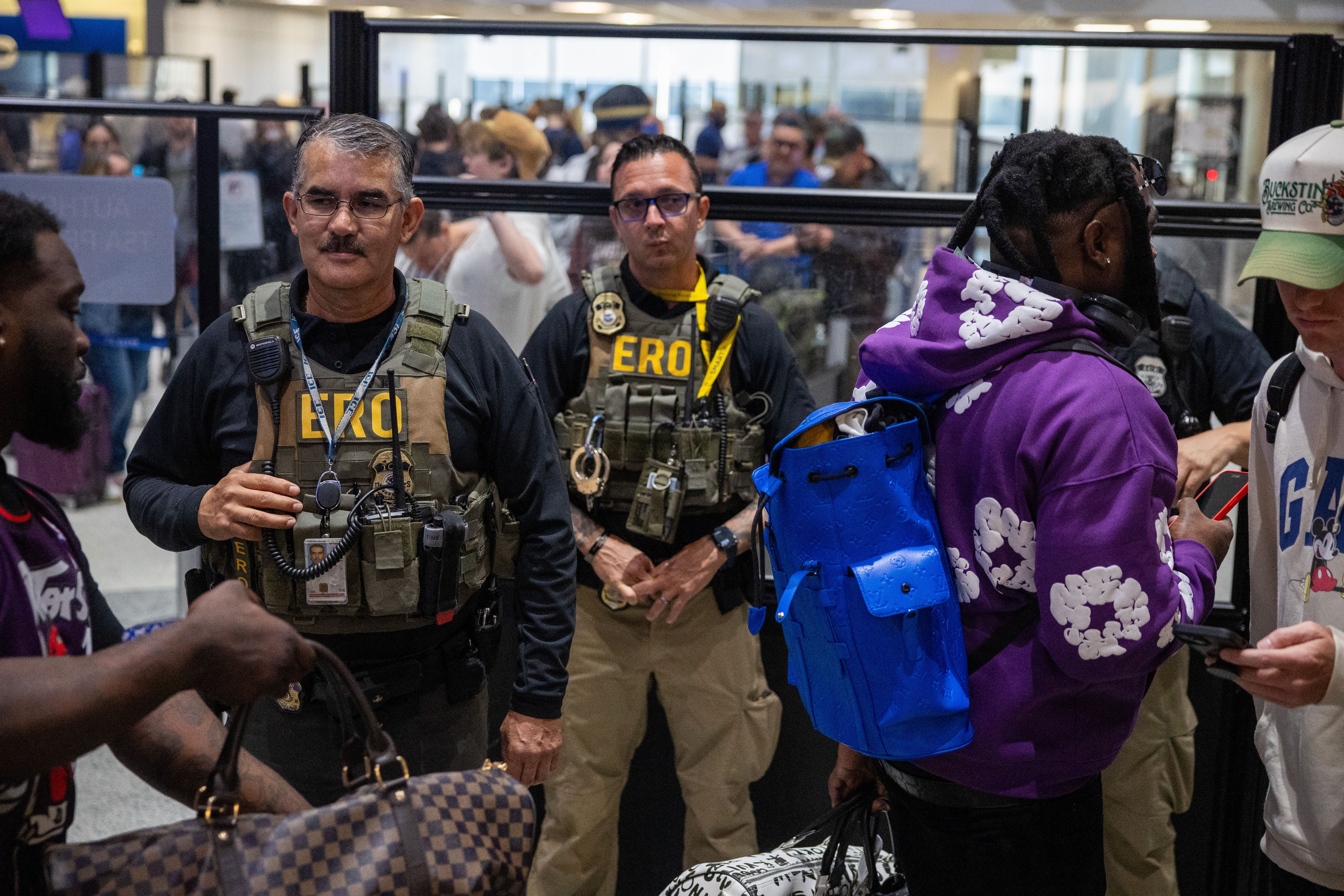 ICE agents stand near crowded airport security lines in Houston as travelers wait during disruptions. Photo: Antranik Tavitian/Getty Images
