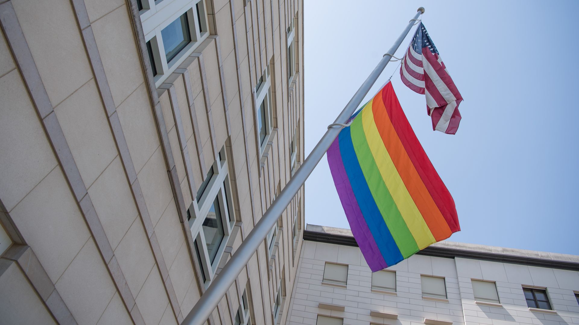 A rainbow flag hangs under a US flag at the US embassy in Berlin, Germany.