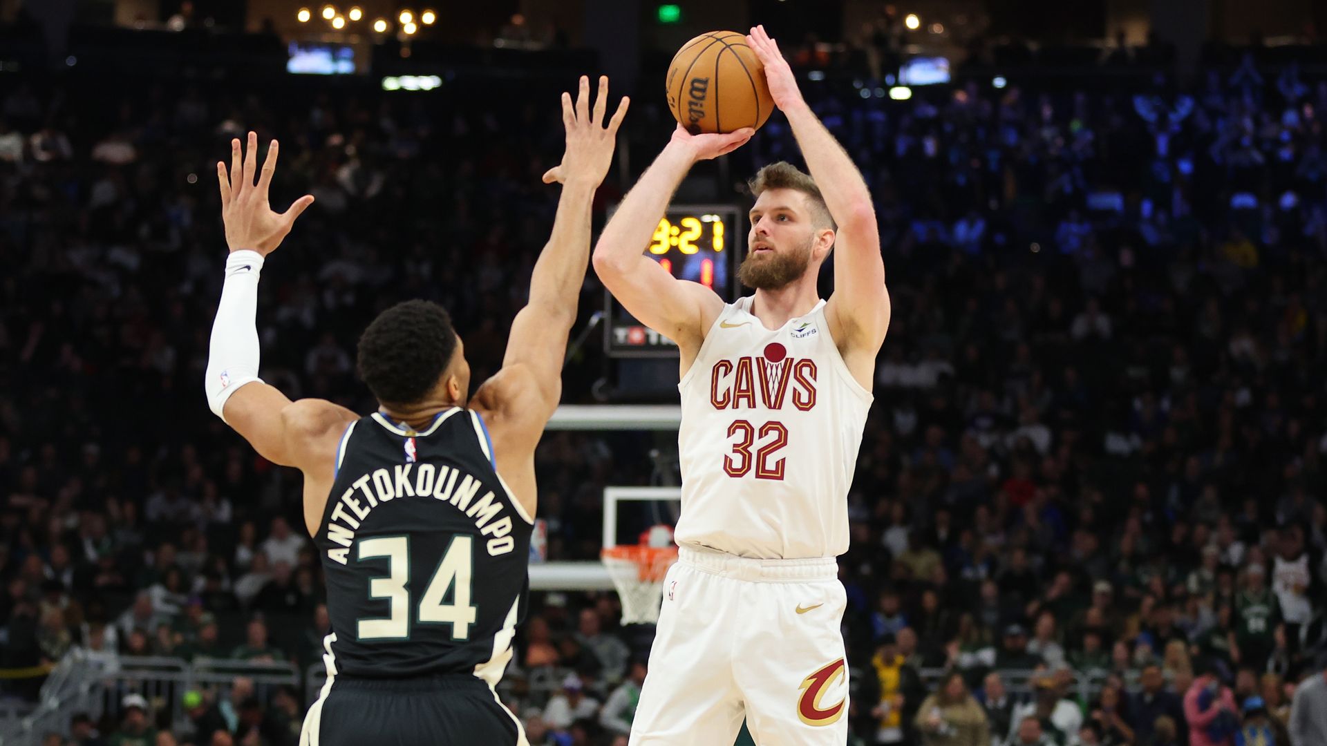 The Cavs' Dean Wade (white jersey) takes a jump shot over the Bucks' Giannis Antetokounmpo (black jersey) 
