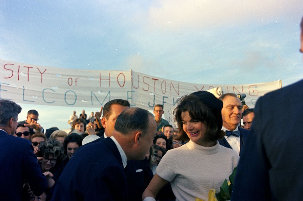 President John F. Kennedy (far left, with back to camera) greets people in the crowd as First Lady Jacqueline Kennedy (right) talks to an unidentified man at Houston International Airport in Houston.