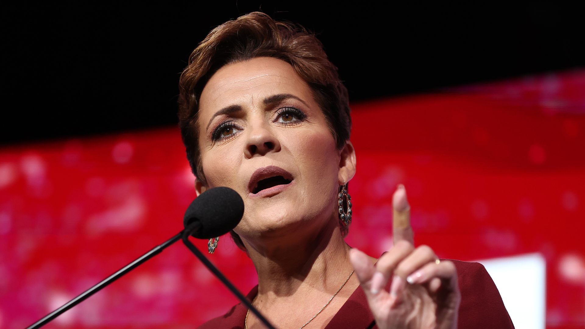 Kari Lake holds up a finger while speaking into a microphone