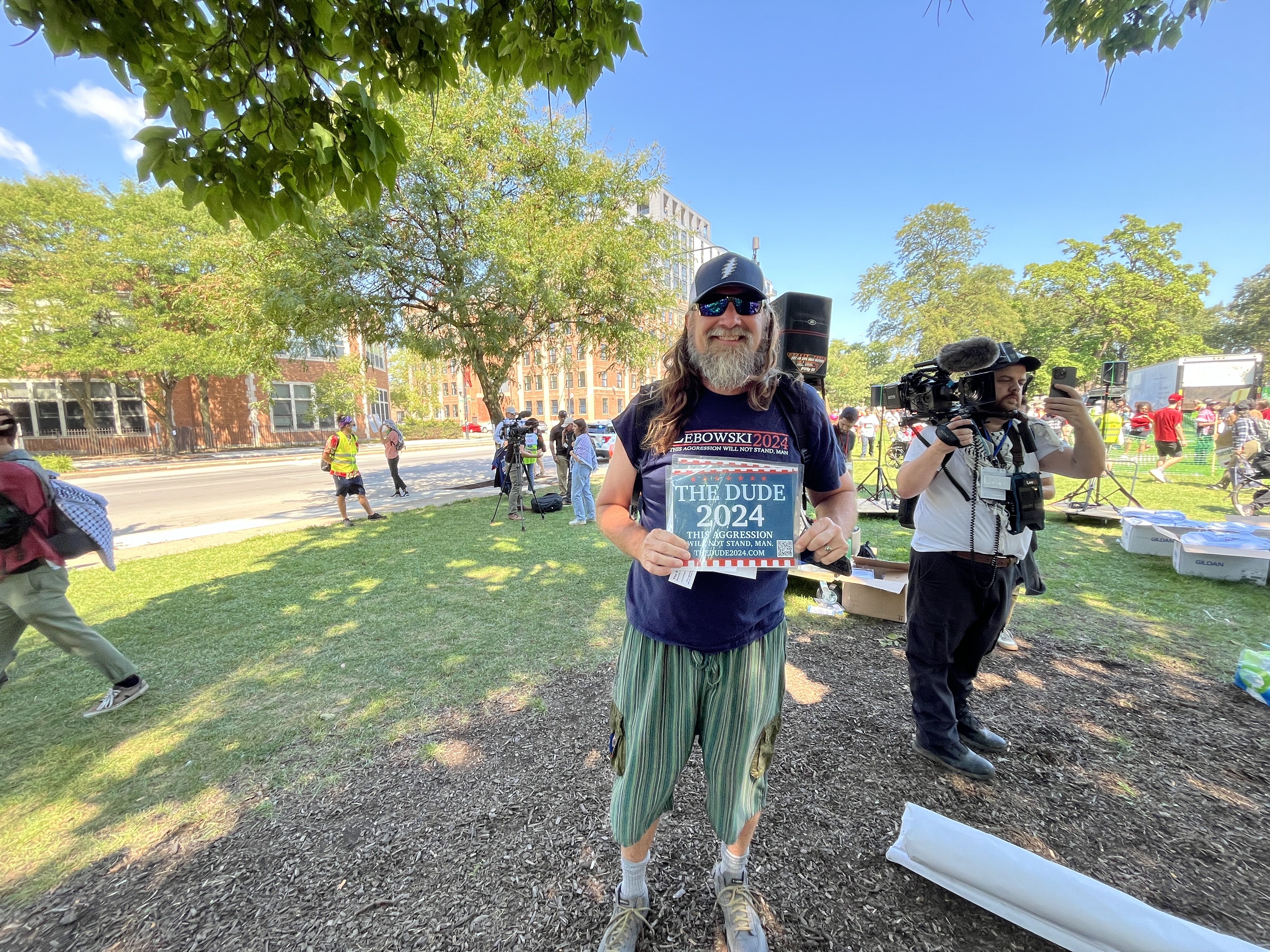 man holds a sign that says "the dude 2024"