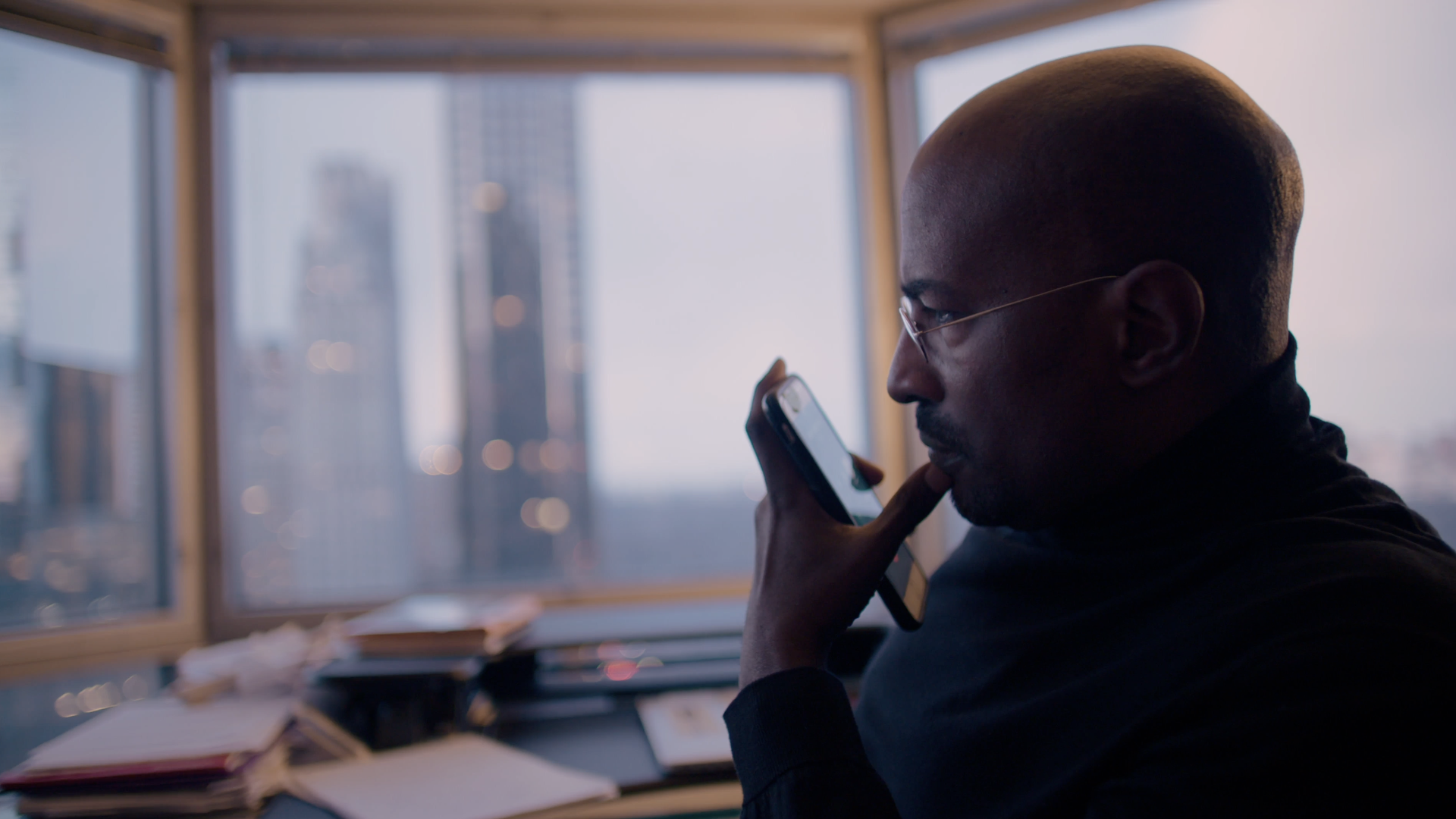 CNN commentator Van Jones talks on the phone in his apartment in front of skyscappers. 
