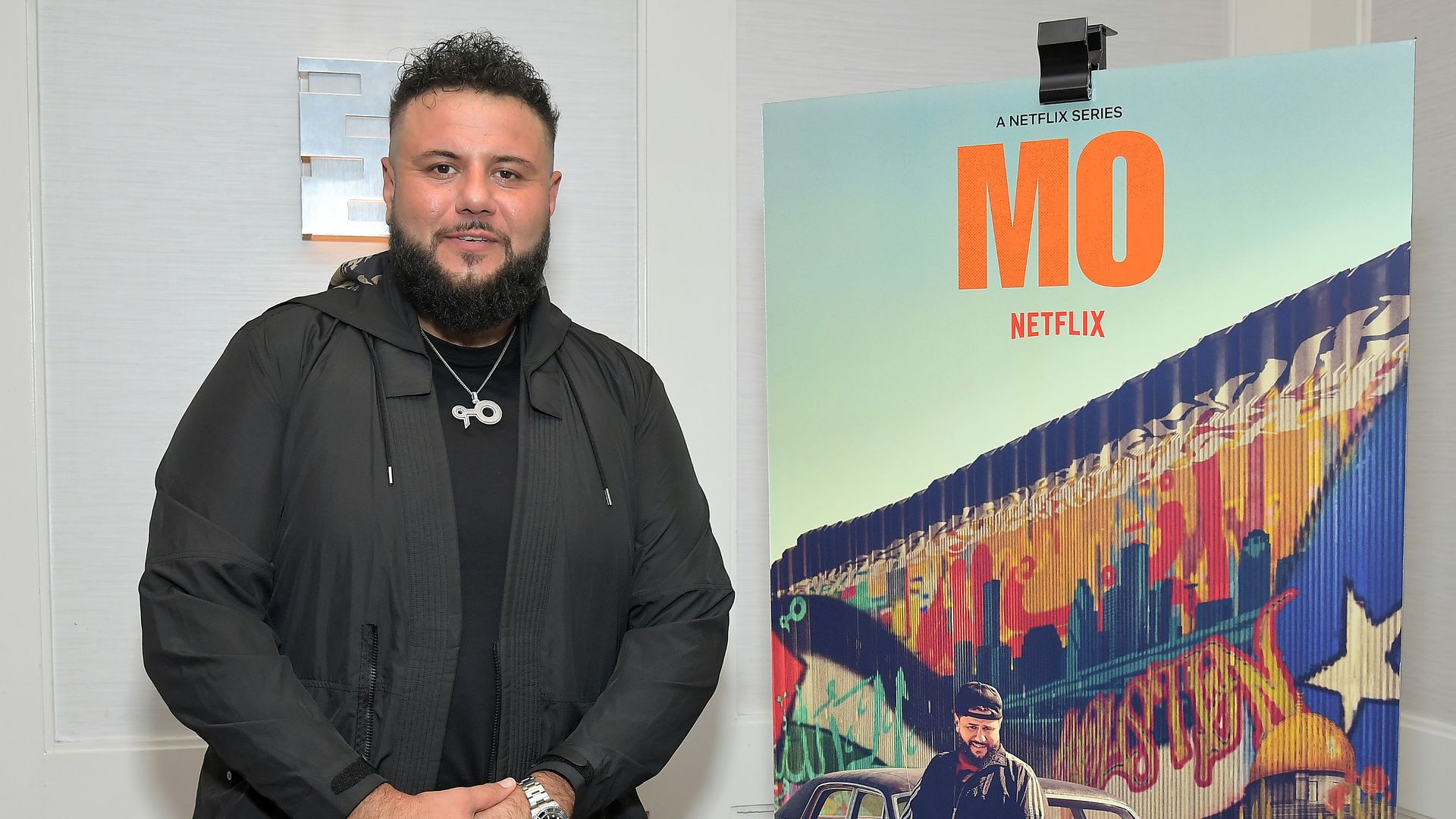 Photo of actor Mo next to a poster of his new show.